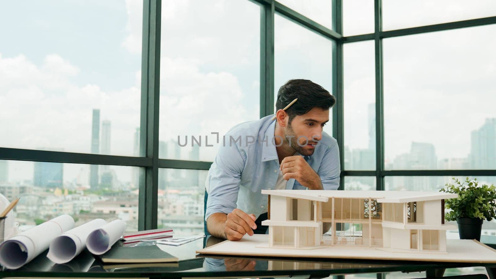 Smart caucasian engineer or project manager measure check, inspect, look at house model while standing near panorama window with city, skyscraper view. Manager design house construction. Tracery