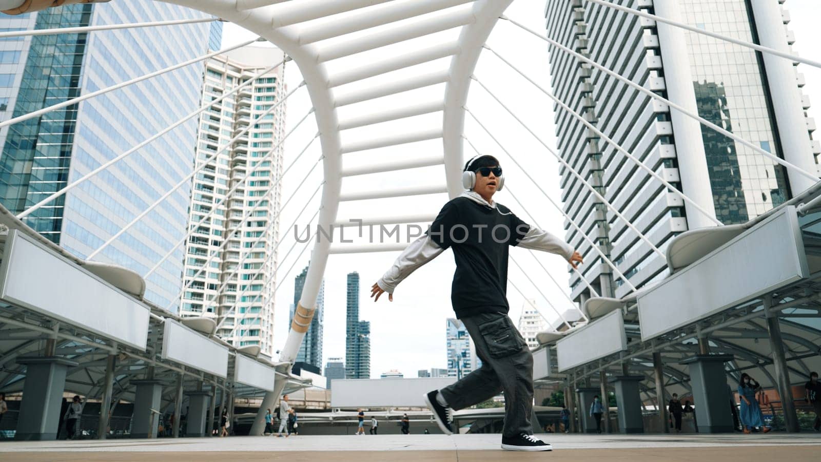 Young asian hipster show footstep at city center surround by people. Stylish fashion street dancer perform B-boy or freestyle dancing with low angle. Outdoor sport 2024. Break dancing. Sprightly.