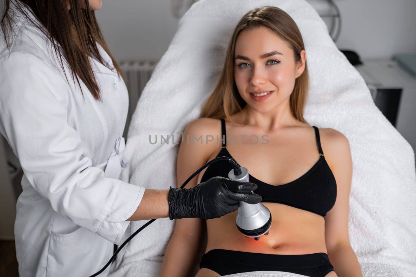 Young blonde woman getting RF lifting of body in a beauty salon.
