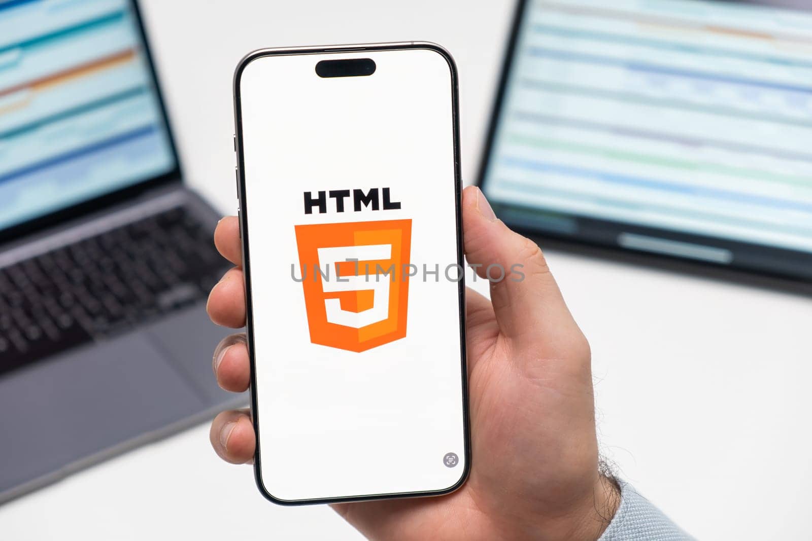 PRAGUE, CZECH REPUBLIC - JANUARY 21 2024: HTML logo on the screen of smartphone in mans hand on the workplace background.