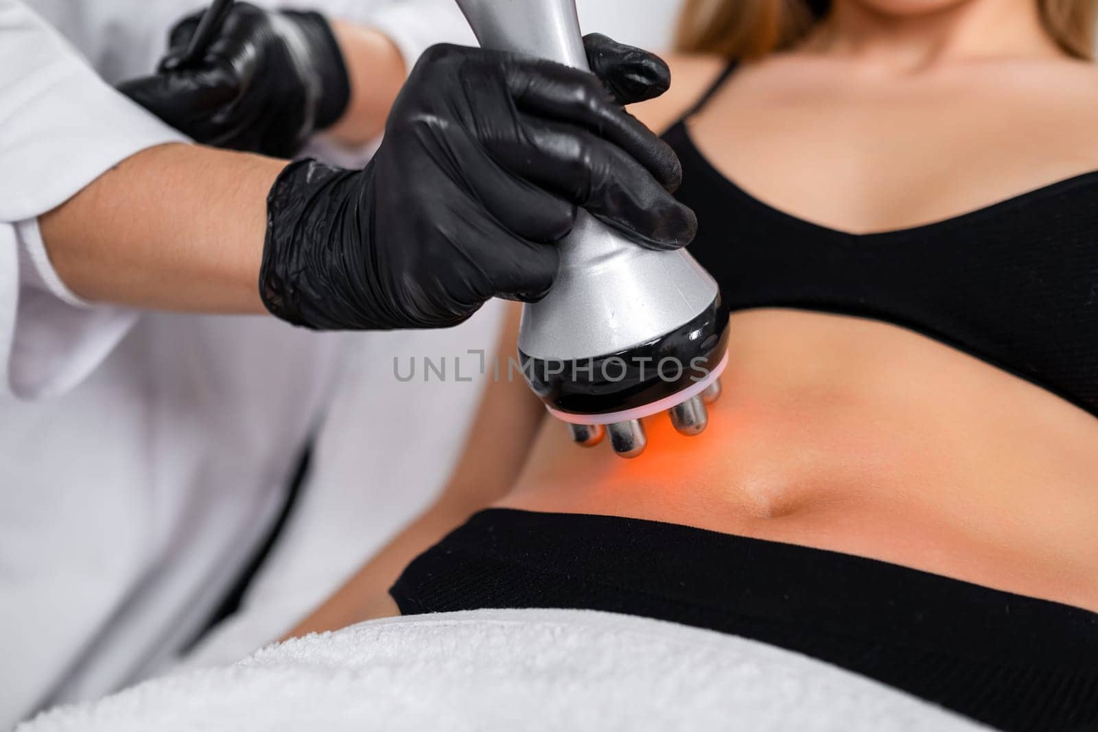 RF body cavitation lifting procedure to reduce fat in belly to young woman in a beauty salon