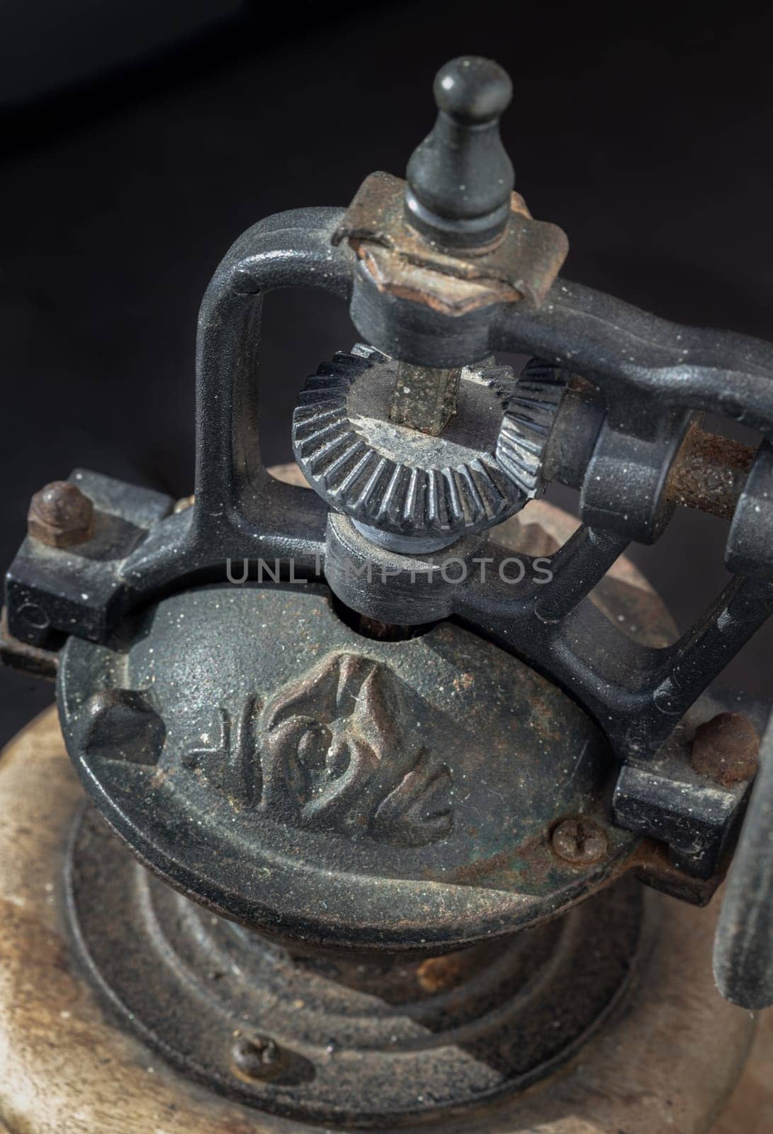 Detail of Antique coffee bean original grinder metal shake wheel with hand crank on dark background.  by tosirikul