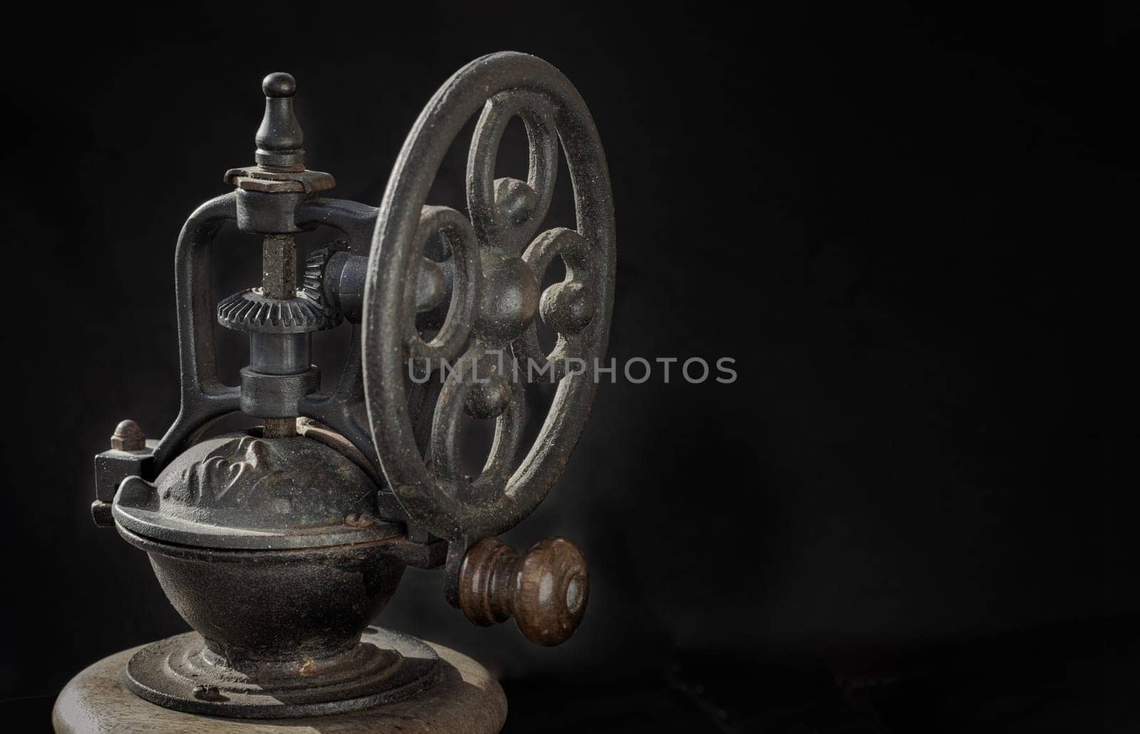 Detail of Antique coffee bean original grinder metal shake wheel with hand crank on dark background.  by tosirikul