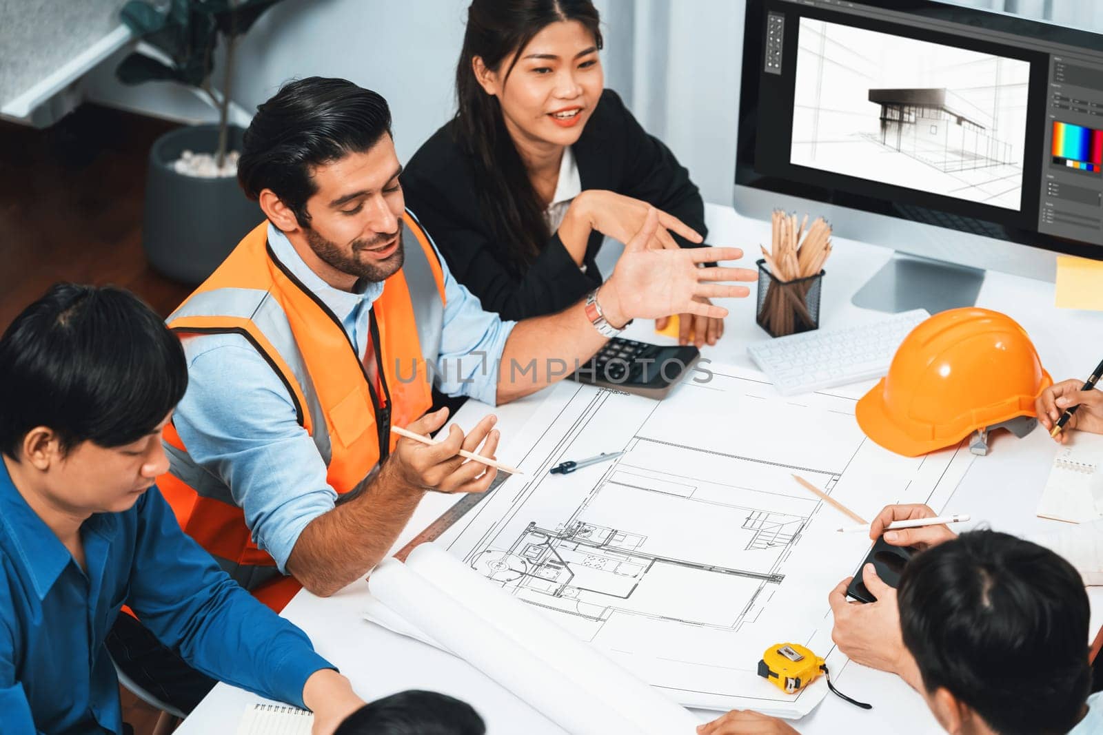 Diverse group of civil engineer and client working together on architectural project, reviewing construction plan and building blueprint at meeting table. Prudent