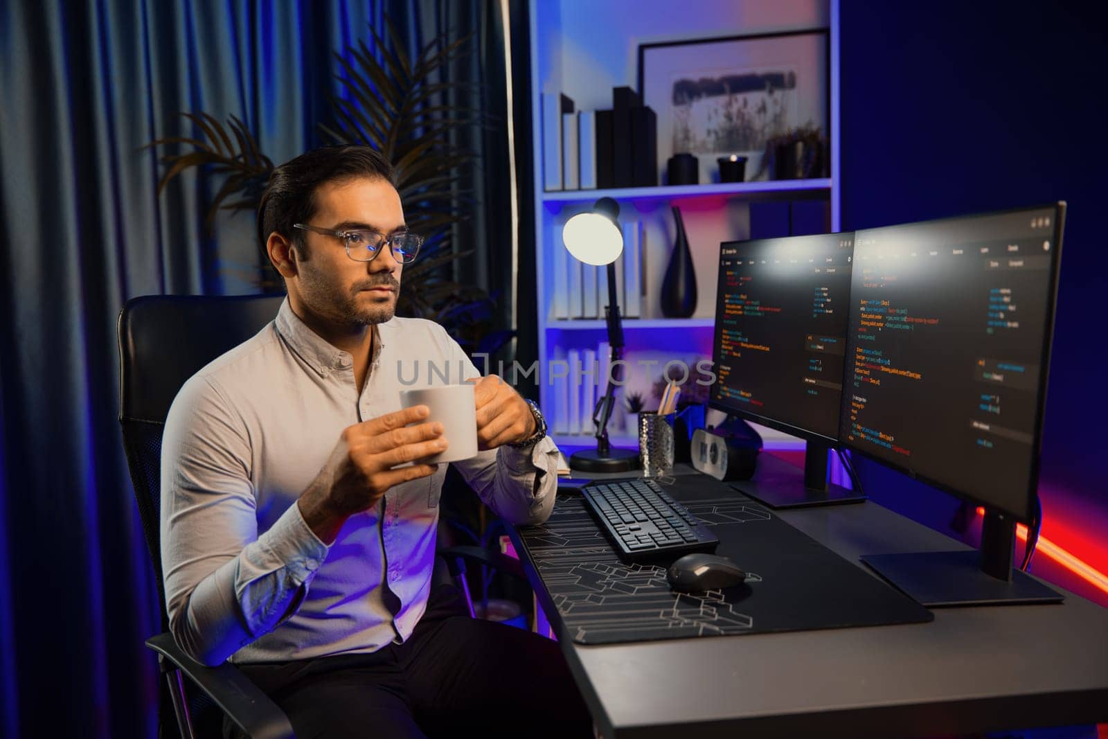 Smart IT developer drinking coffee cup while working in software development coding on pc screen, presenting program application update online website database at neon lighting cyber office. Surmise.