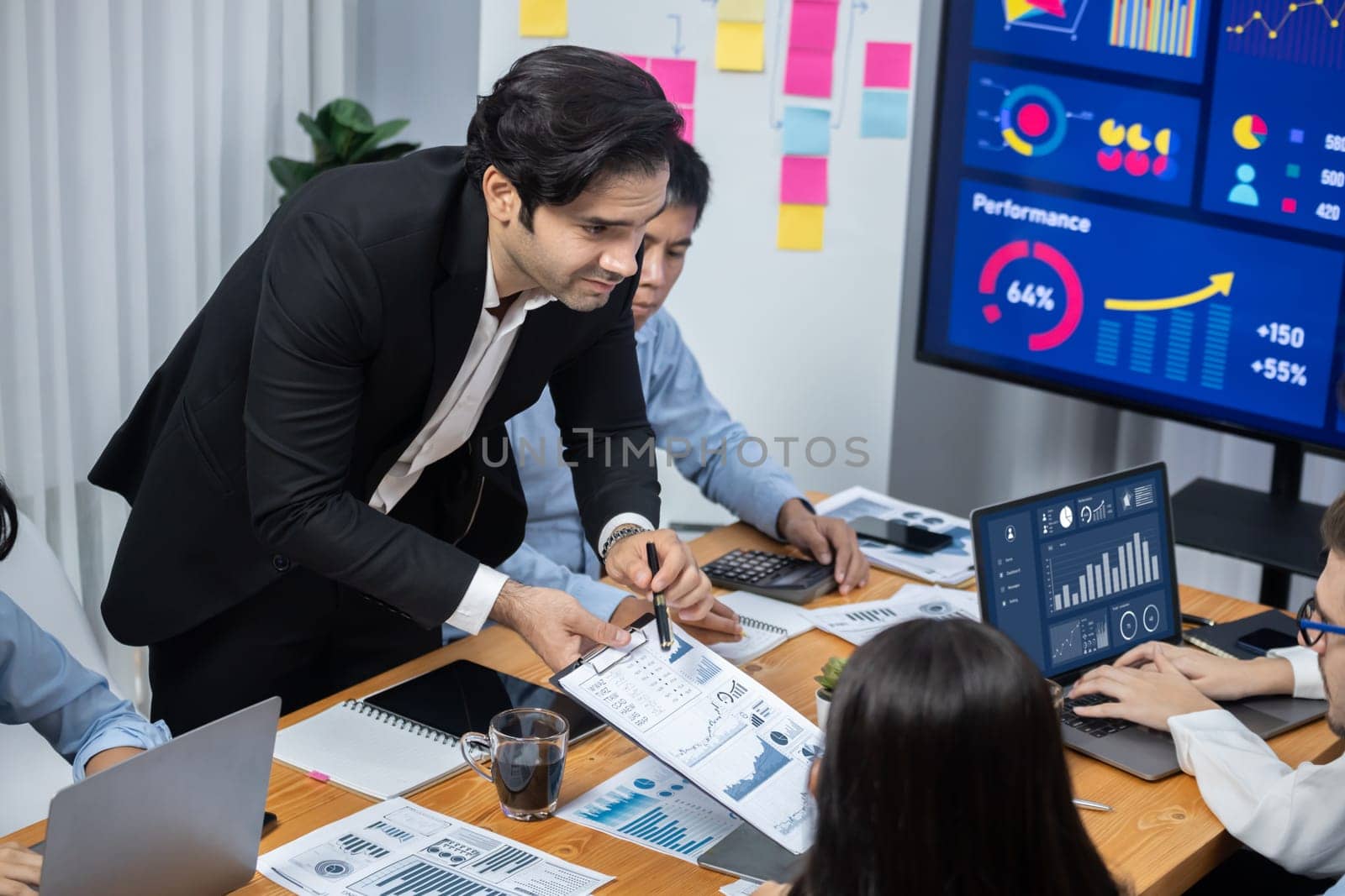 Wide top view of diverse group of business analyst team analyzing financial data report paper on meeting table. Chart and graph dashboard by business intelligence analysis. Meticulous