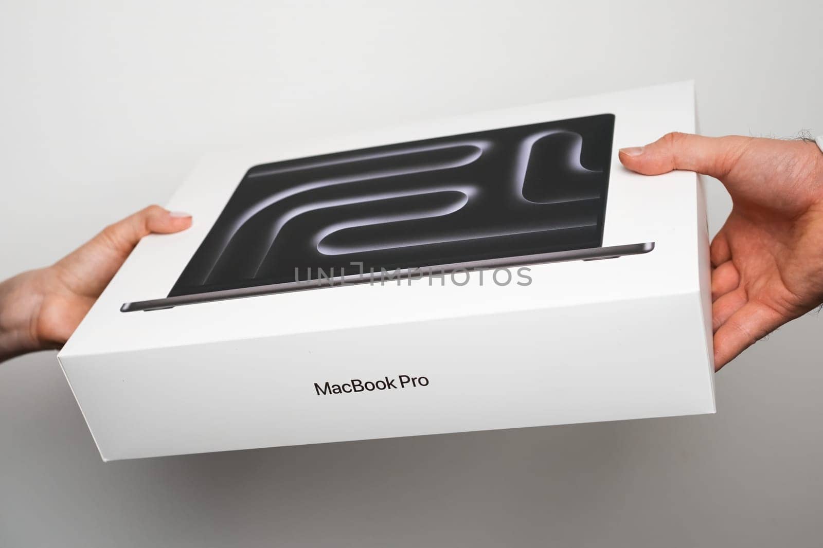 BERLIN , GERMANY - FEBRUARY 14 2024: MacBook Pro in mans and womans hands on the white background.