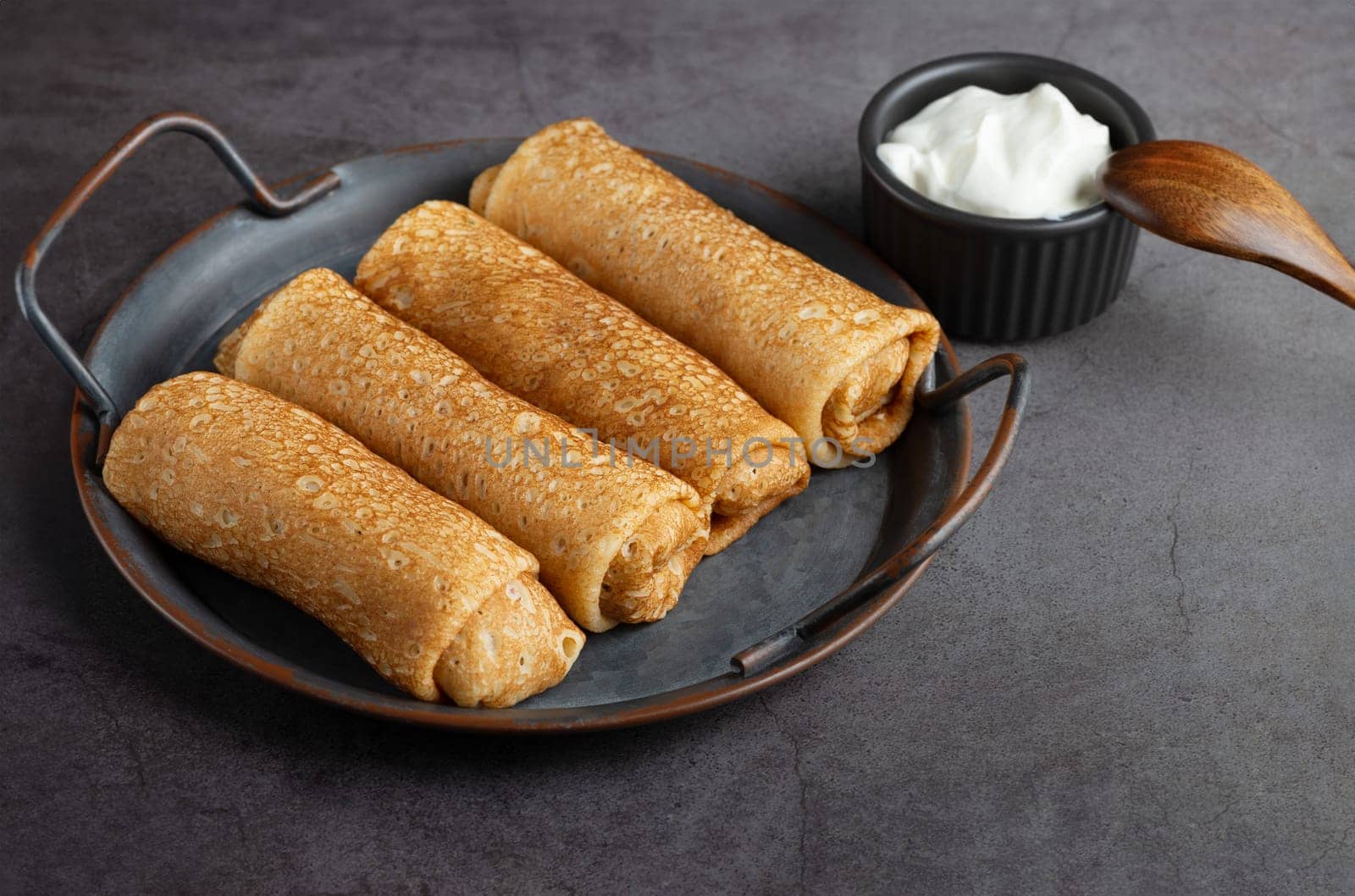Thin pancakes or crepes stuffed with cottage cheese on grey background.