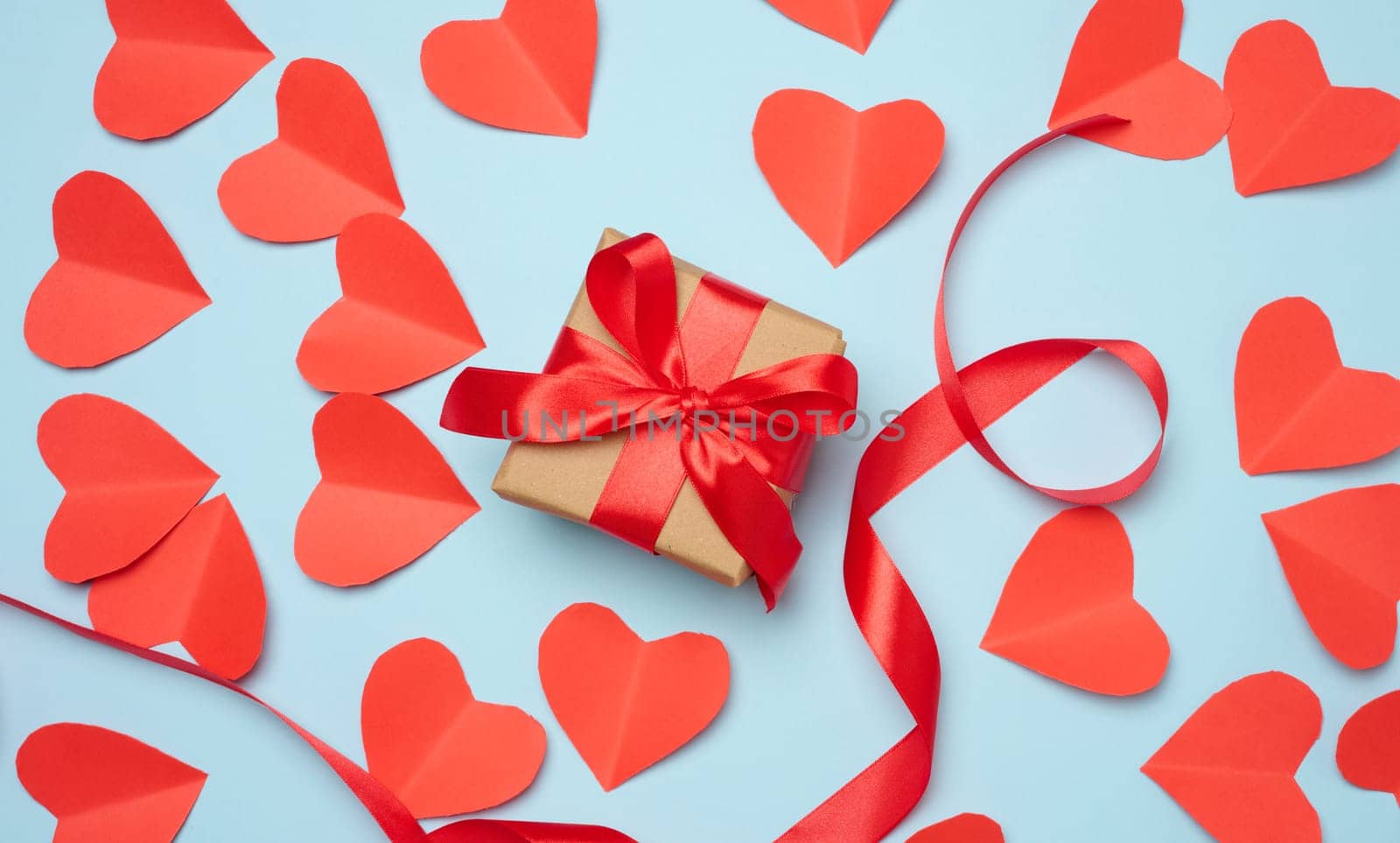 Gift box with red satin ribbon and bow on a blue background.Holiday background by ndanko