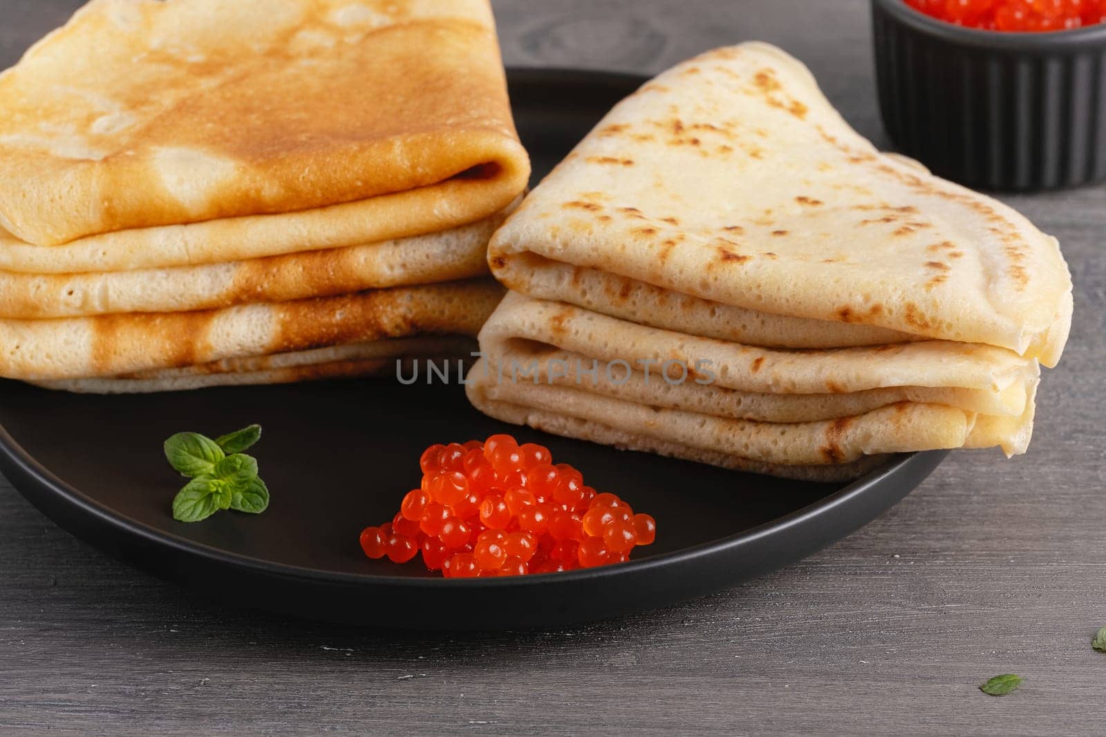 Pancakes with red caviar. Close-up of pancakes stacked on grey background.