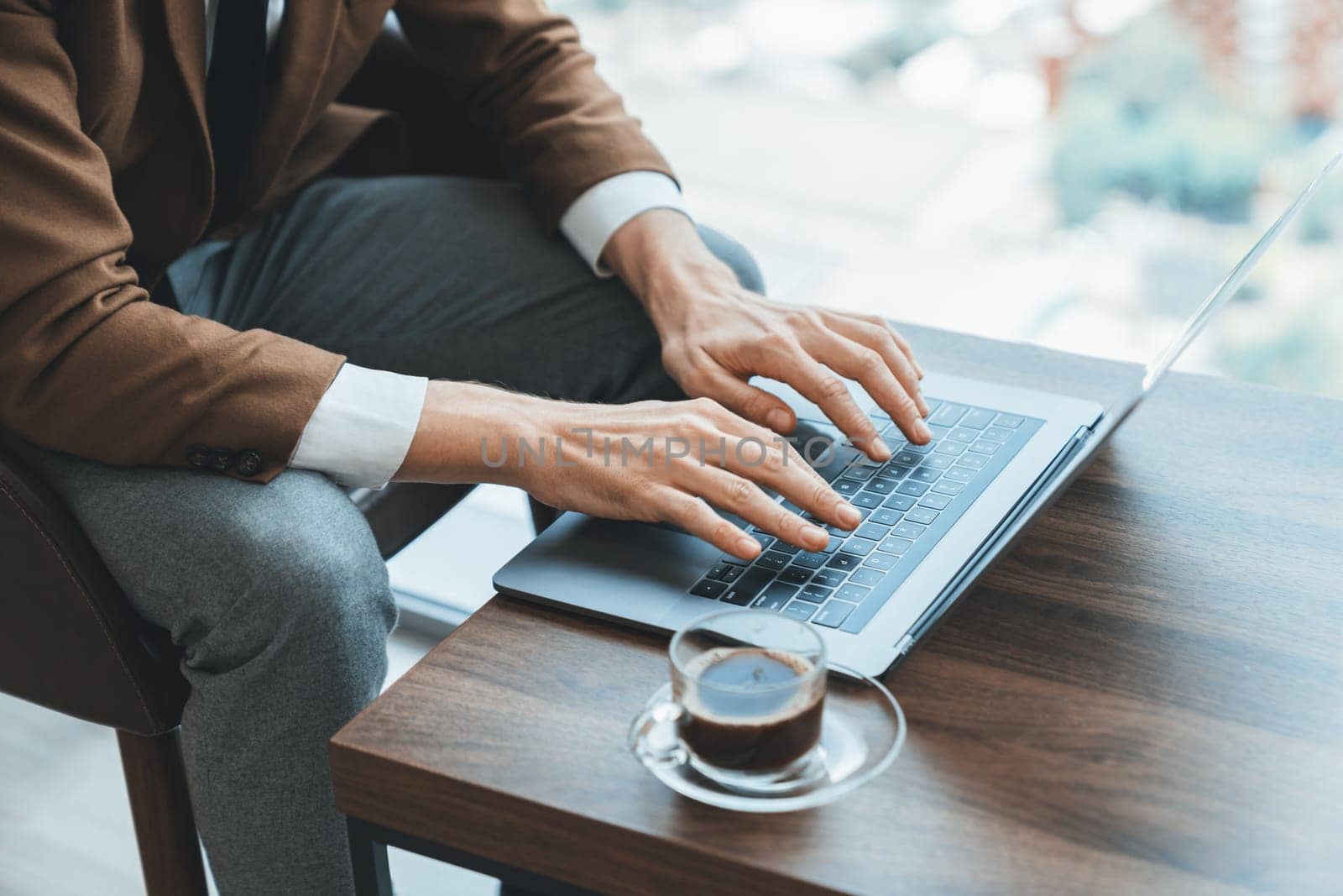 Top view of smart businessman hand searching, typing,analyzing data by using laptop. Closeup image of manager hands working with laptop on wooden desk with coffee cup surrounded by nature. Ornamented.
