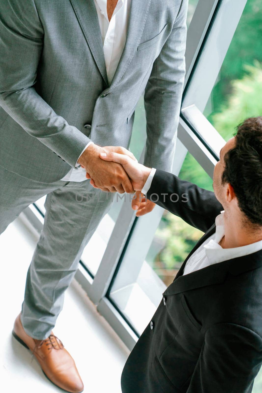 Businessman handshake with another businessman partner in modern workplace office. People corporate business deals concept. uds