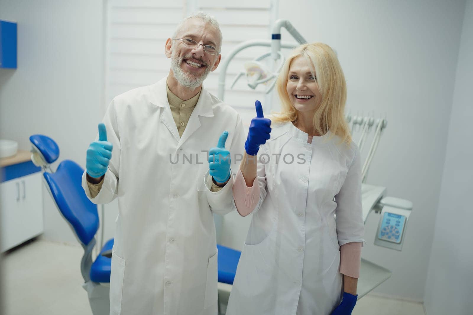 Male and female dental doctors wearing face sitting at his clinic. High quality photo