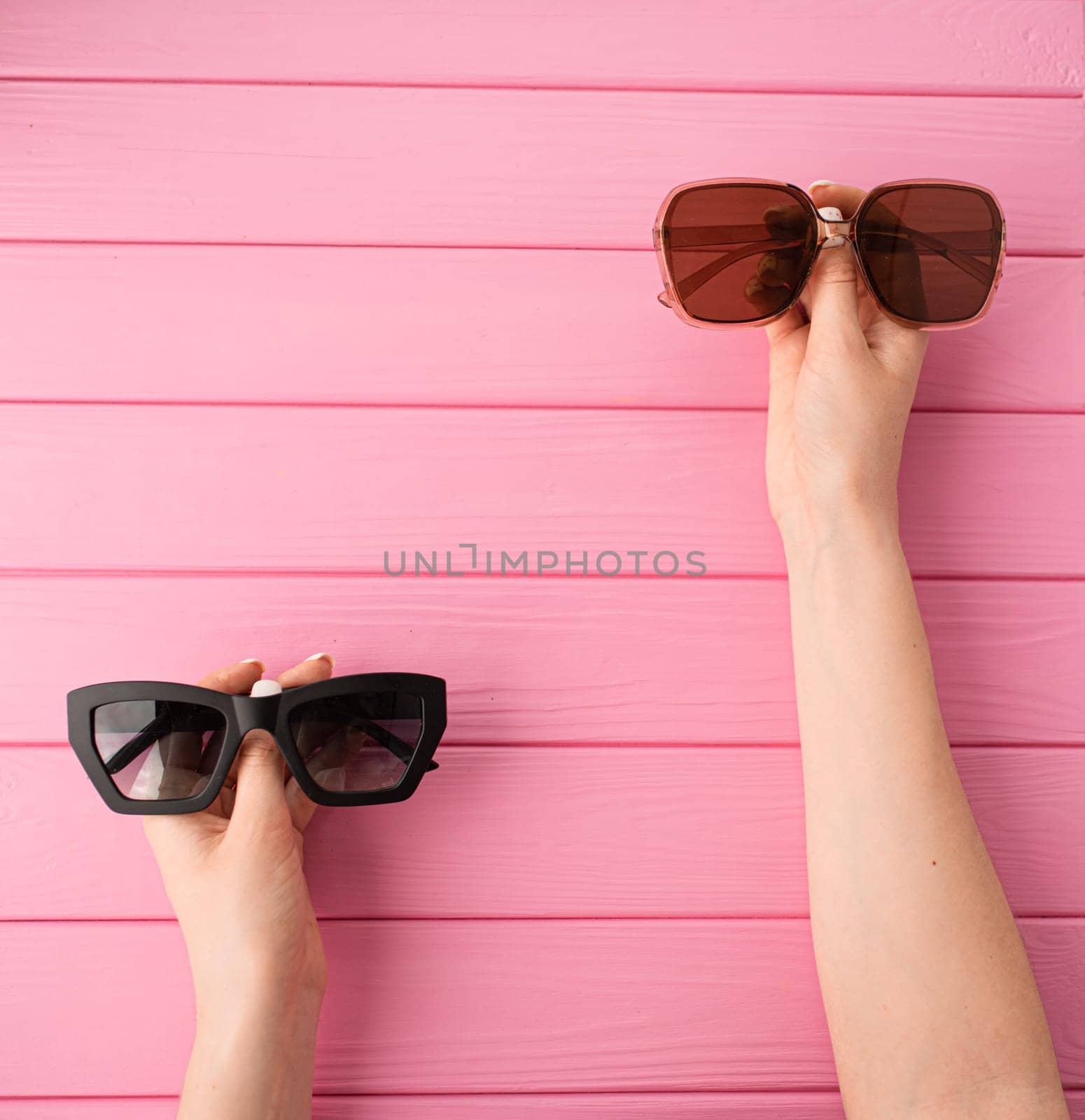 Summer abstract background mockup template free copy space for text pattern sample top view above on pink wooden board. blank empty area for inscription woman hands hold Couple sunglasses fashionable