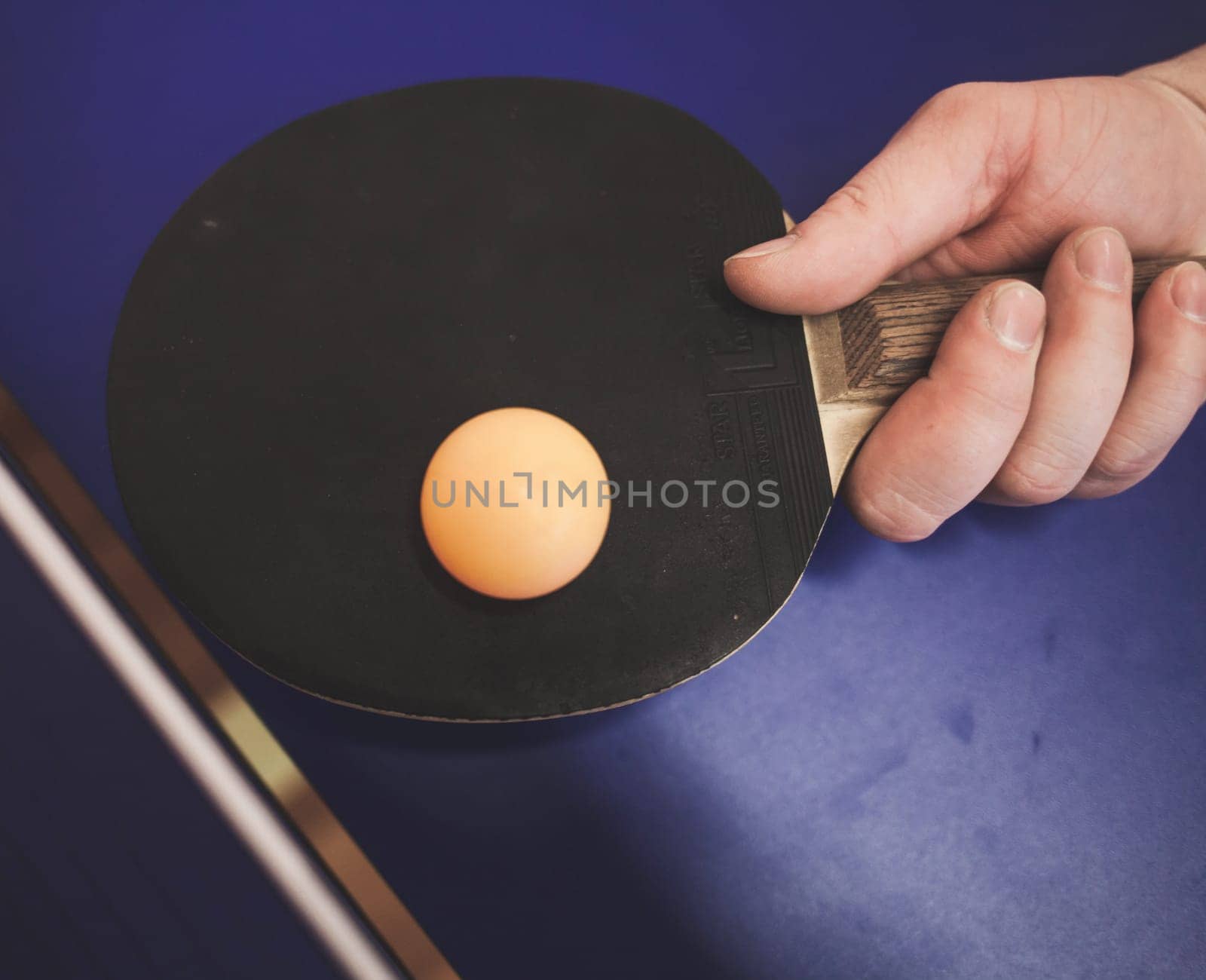 man is playing ping pong. He holds racket in his hands