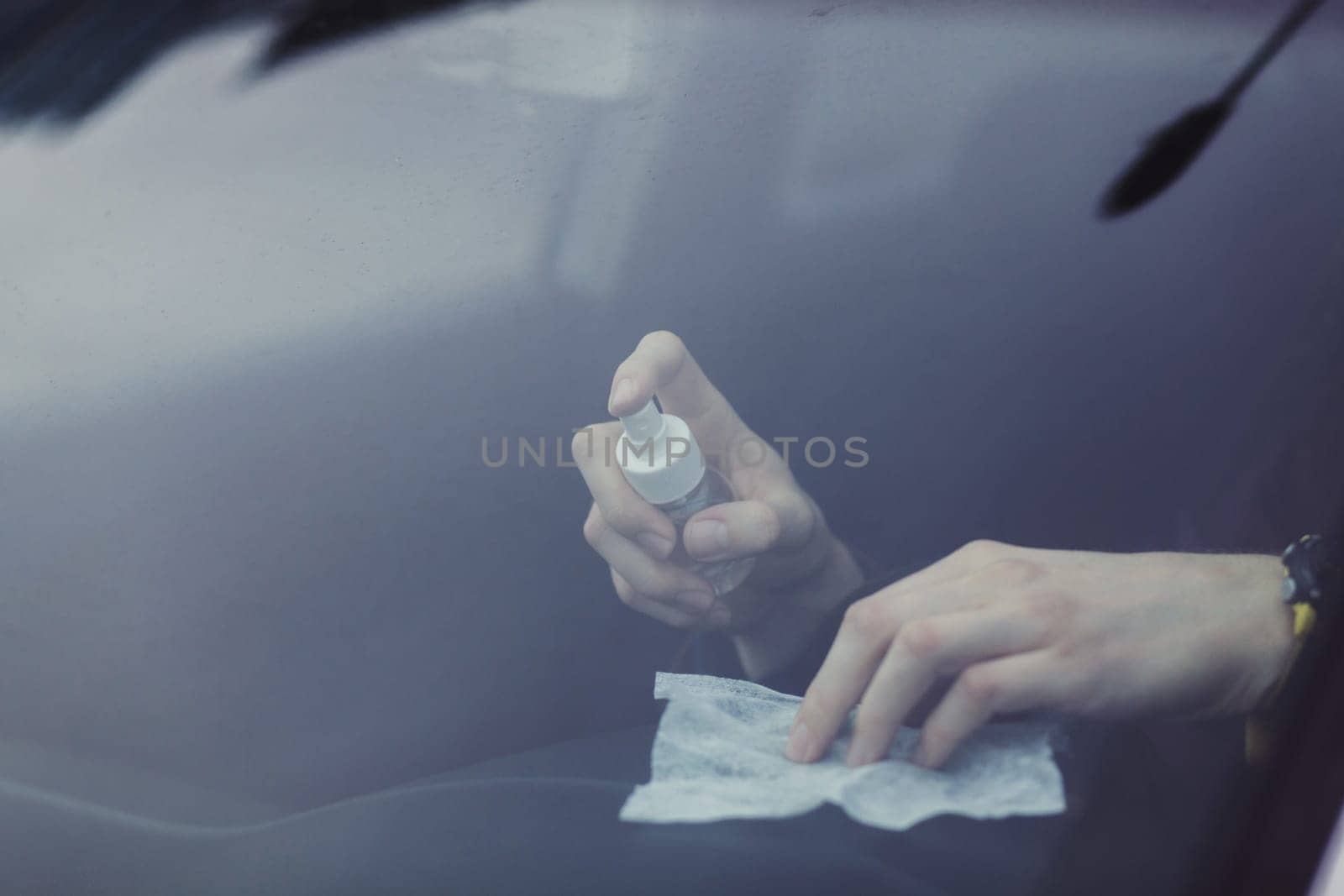 the driver cleans the car with antibacterial spray by Ladouski