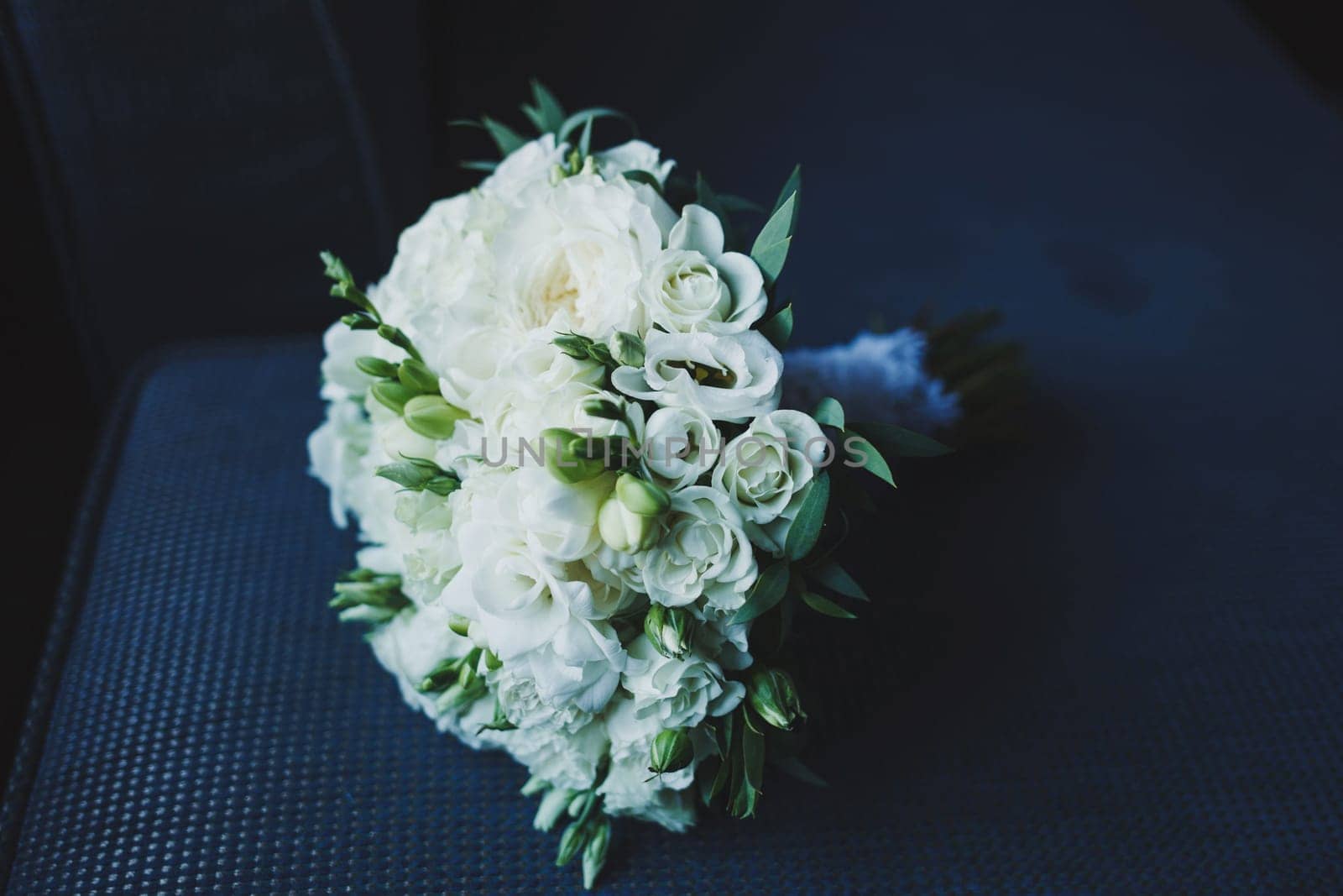 wedding bouquet with roses and other flowers on arm chair