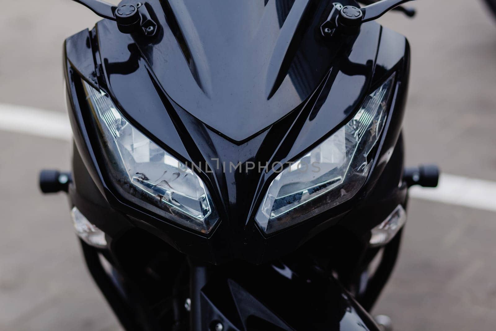 close-up of the headlights of a black sports motorcycle on the street.