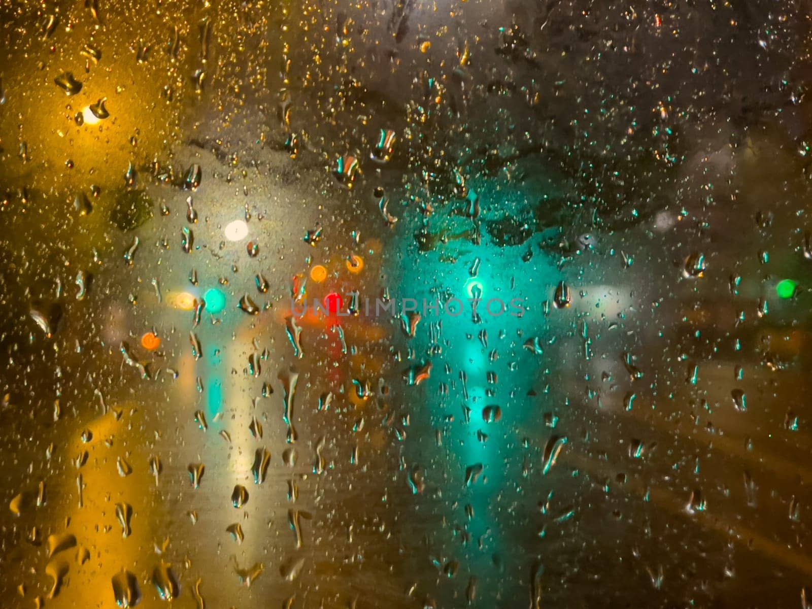 Rain bokeh road lights. Abstract shot of evening city traffic bokeh. Multicolored lights of the evening city and passing cars through a wet rainy window