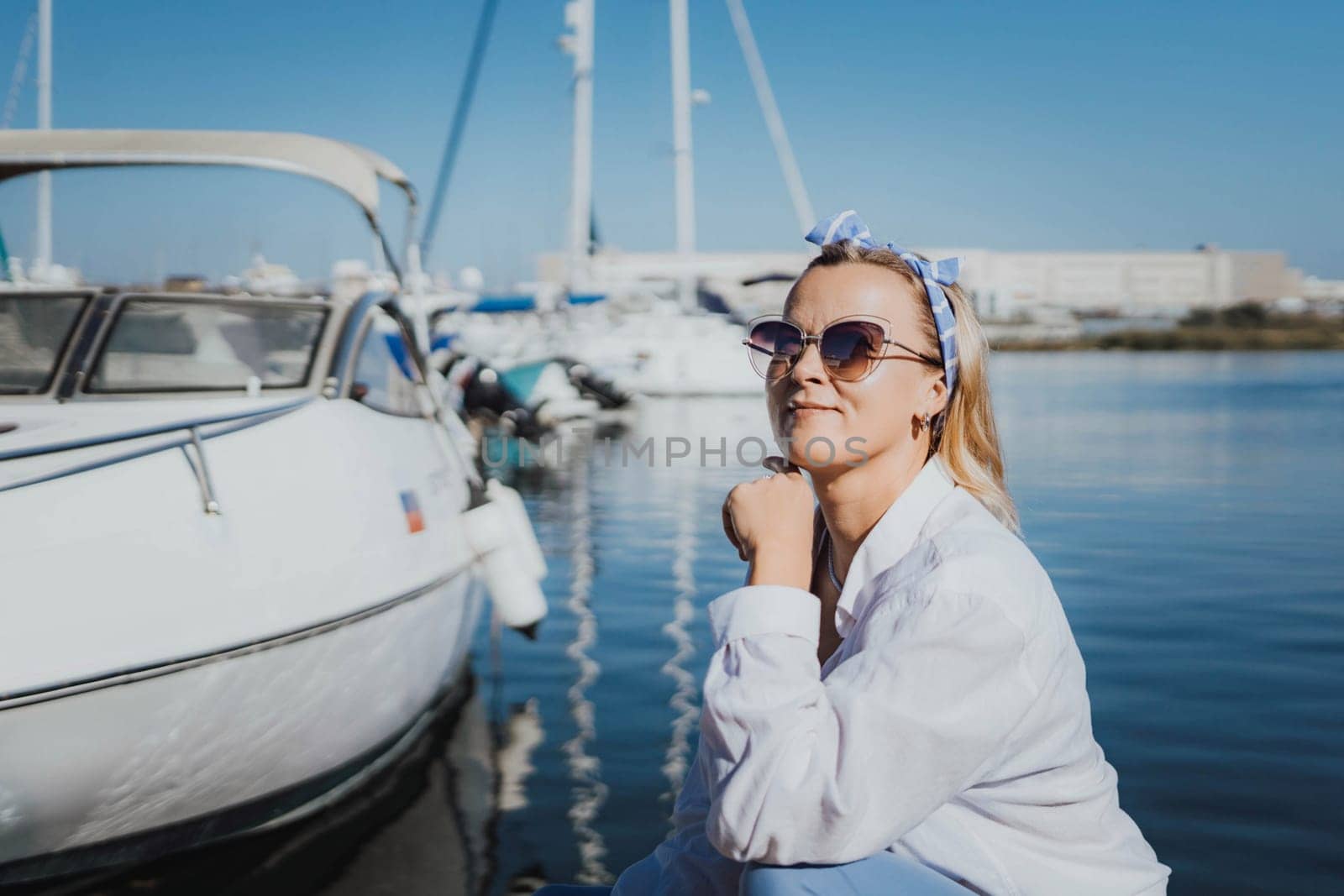 Woman in white shirt in marina , surrounded by several other boats. The marina is filled with boats of various sizes, creating a lively and picturesque atmosphere