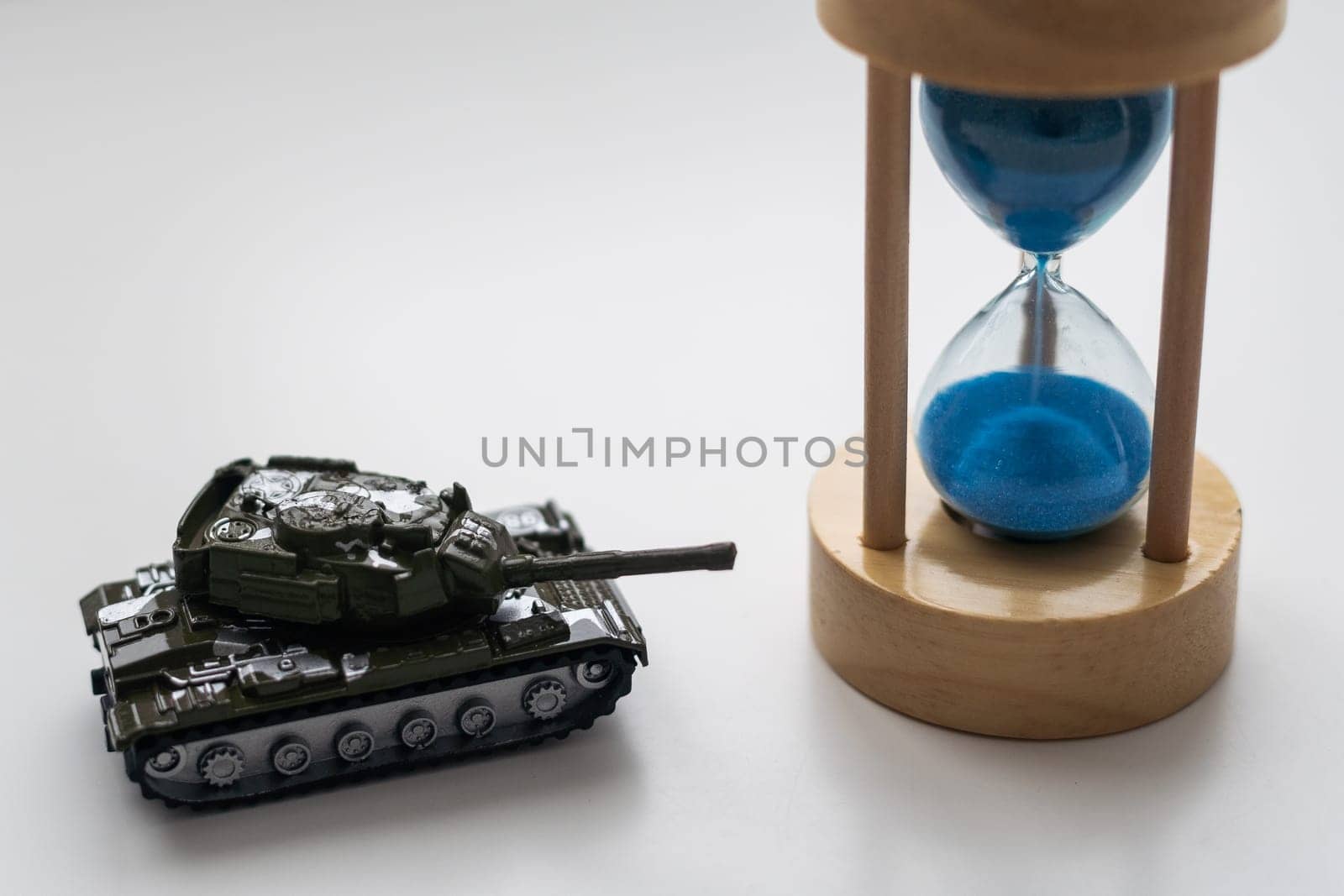 The plastic tank toys on the floor next to an hourglass. High quality photo