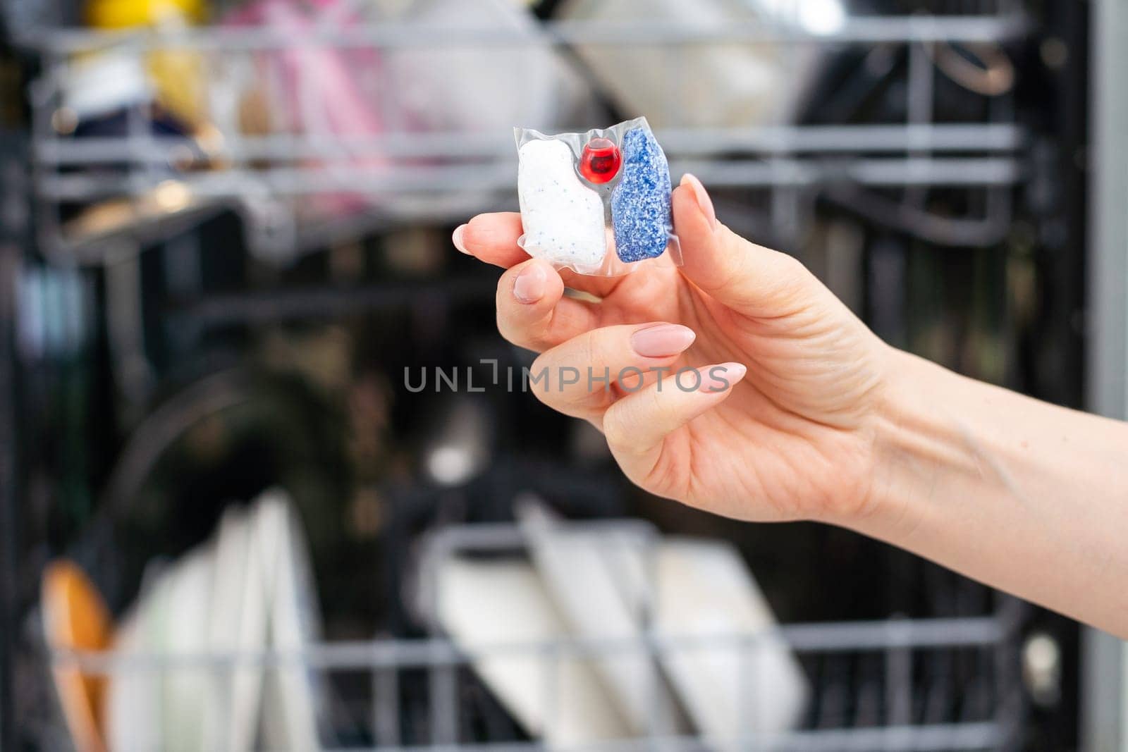 Closeup of hand holding and put detergent clean tablet into a dishwasher tray. High quality photo