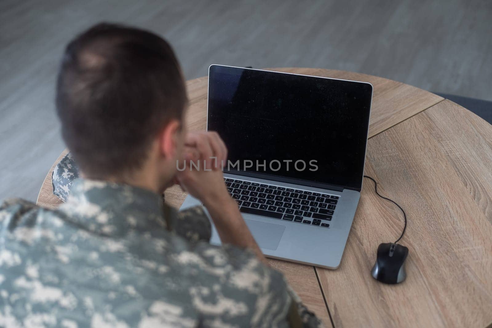 Young hispanic man army soldier using laptop sitting on table at home. High quality photo