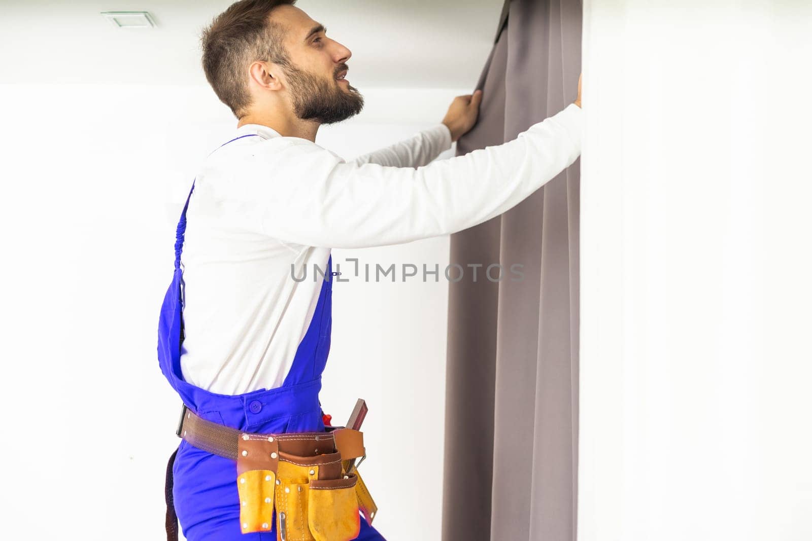 Man hanging window curtain indoors, closeup. Interior decor element.
