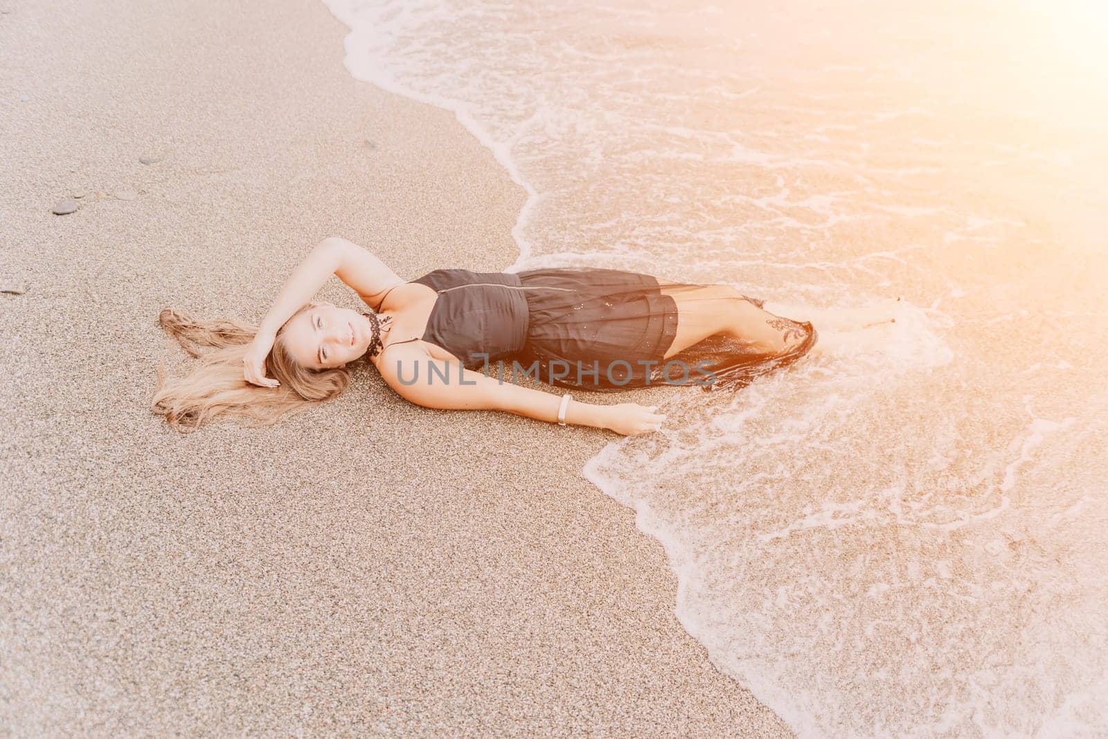 Woman summer travel sea. Happy tourist in black dress enjoy taking picture outdoors for memories. Woman traveler posing on sea beach surrounded by volcanic mountains, sharing travel adventure journey by panophotograph