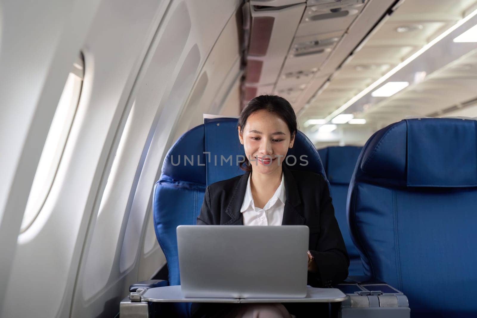 Asian young woman using laptop at first class on airplane during flight, Traveling and Business concept by nateemee