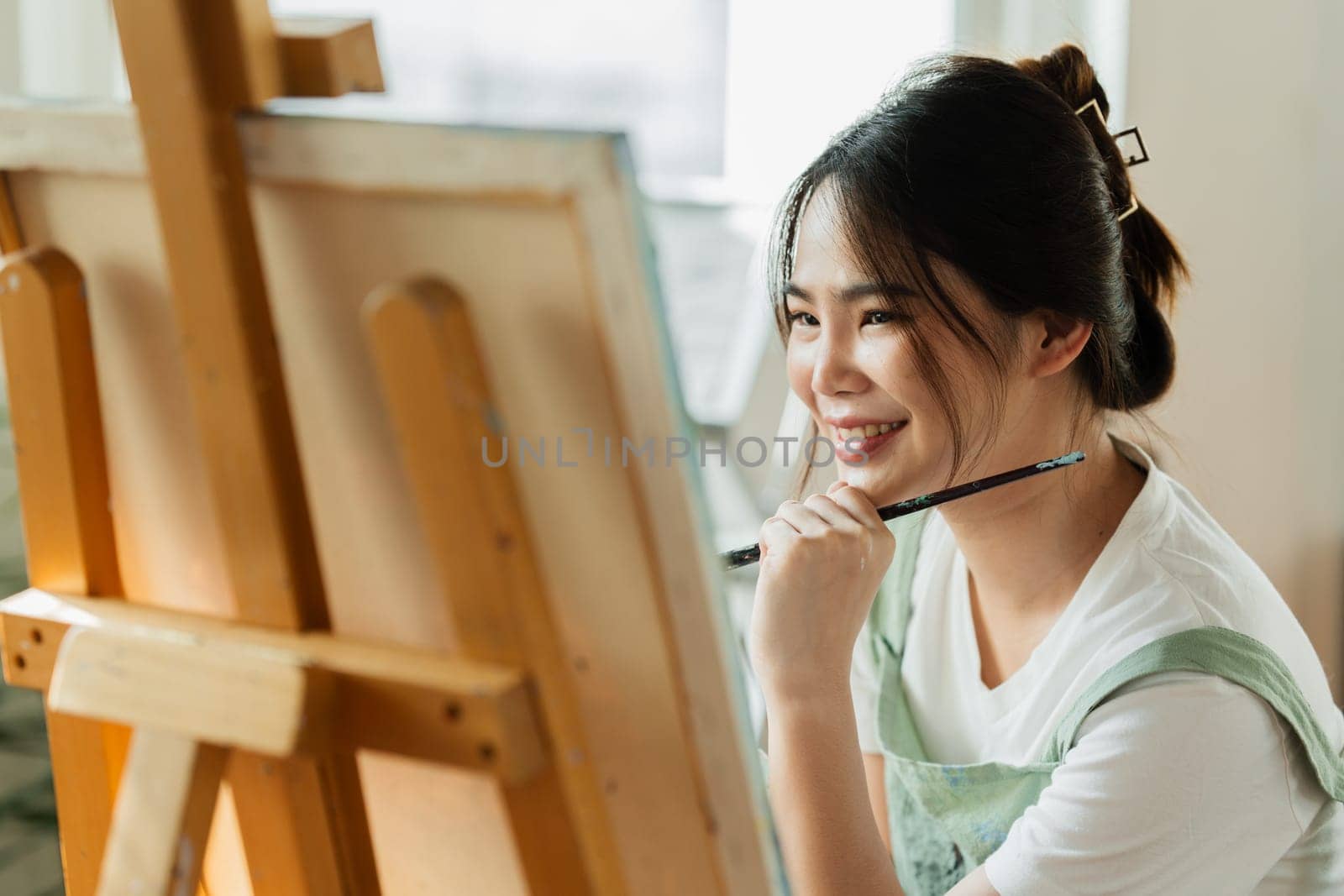 A beautiful young woman artist working on painting something on a large canvas.