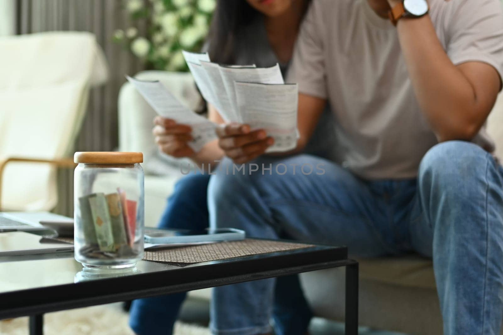 Cropped shot of stressed young couple discussing unpaid debt or money problems at home by prathanchorruangsak