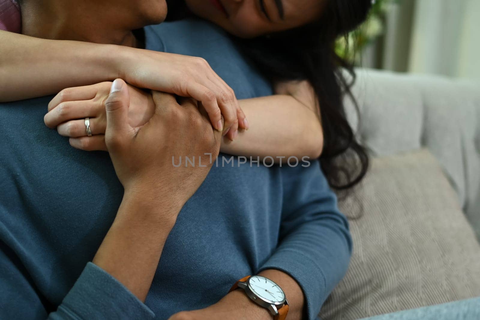 Cropped shot loving woman hugging her husband on couch from behind. Love, relationship and lifestyle concept by prathanchorruangsak