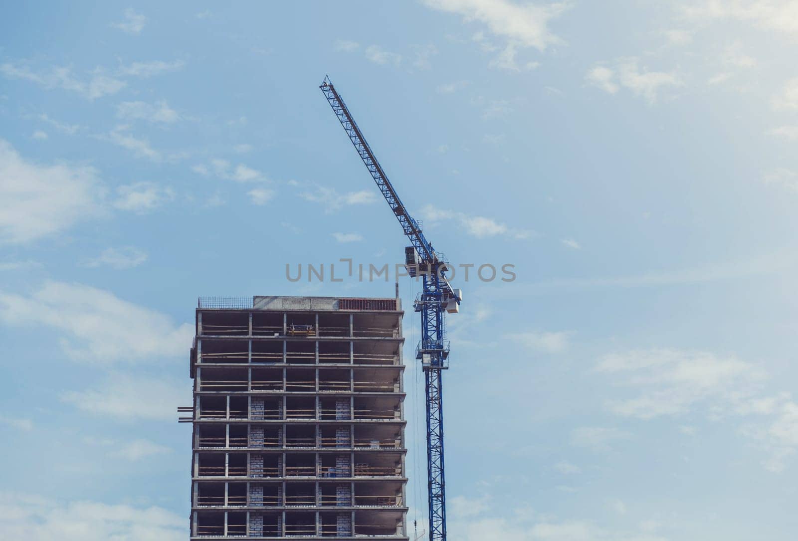 Crane and building under construction against blue sky 