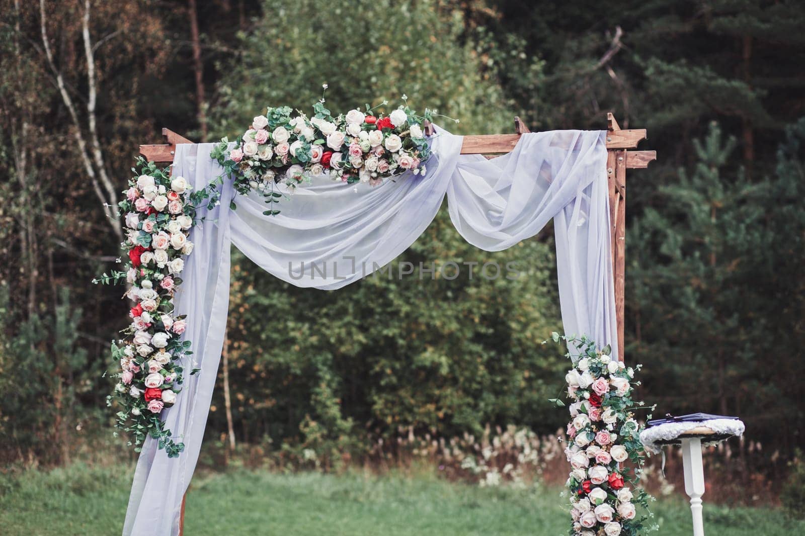 Beautiful wedding ceremony outdoors. Wedding arch made of cloth and flowers
