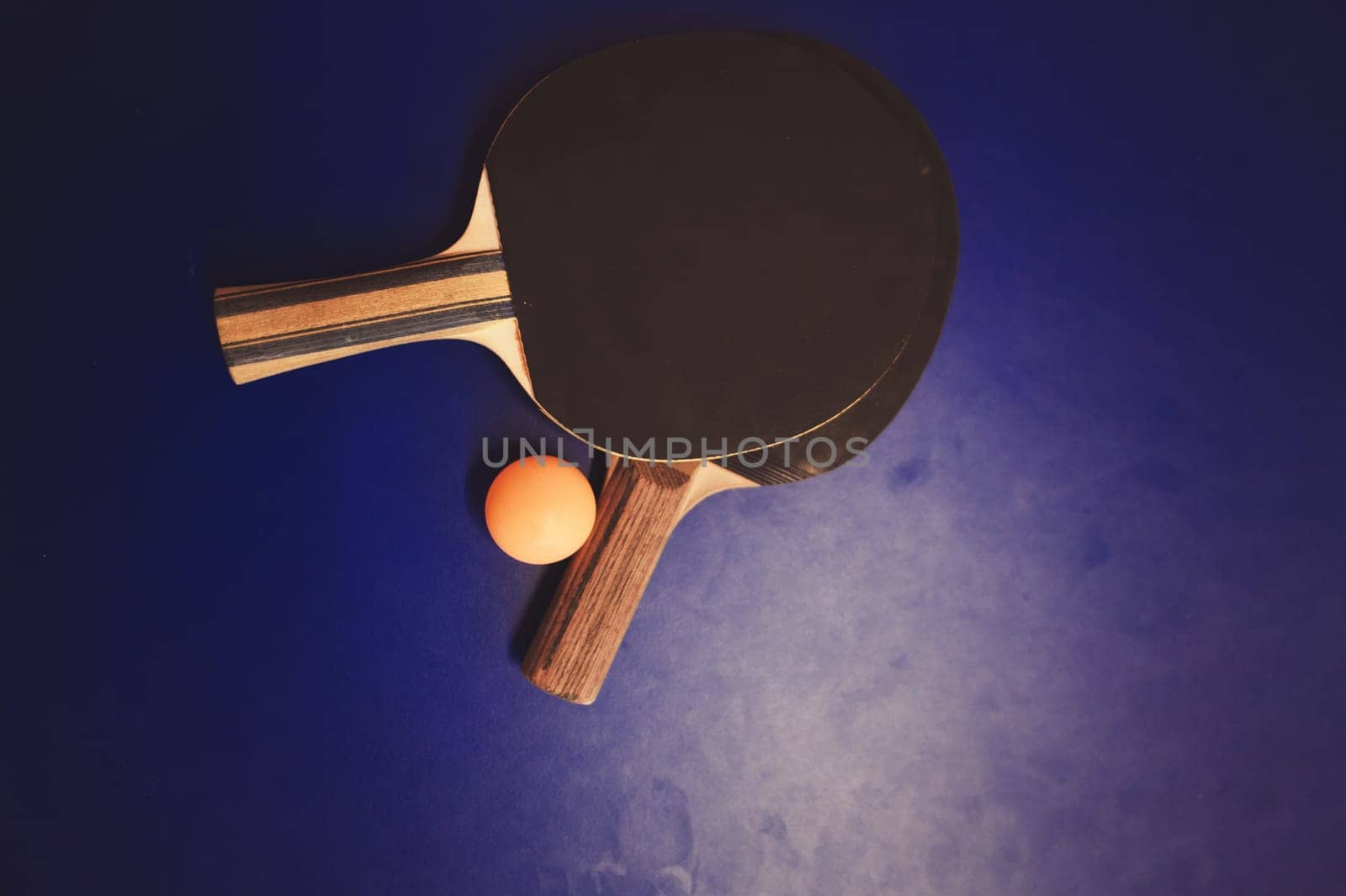 Blue table tennis or ping pong. Two table tennis or ping pong rackets or paddles and ball on a blue table