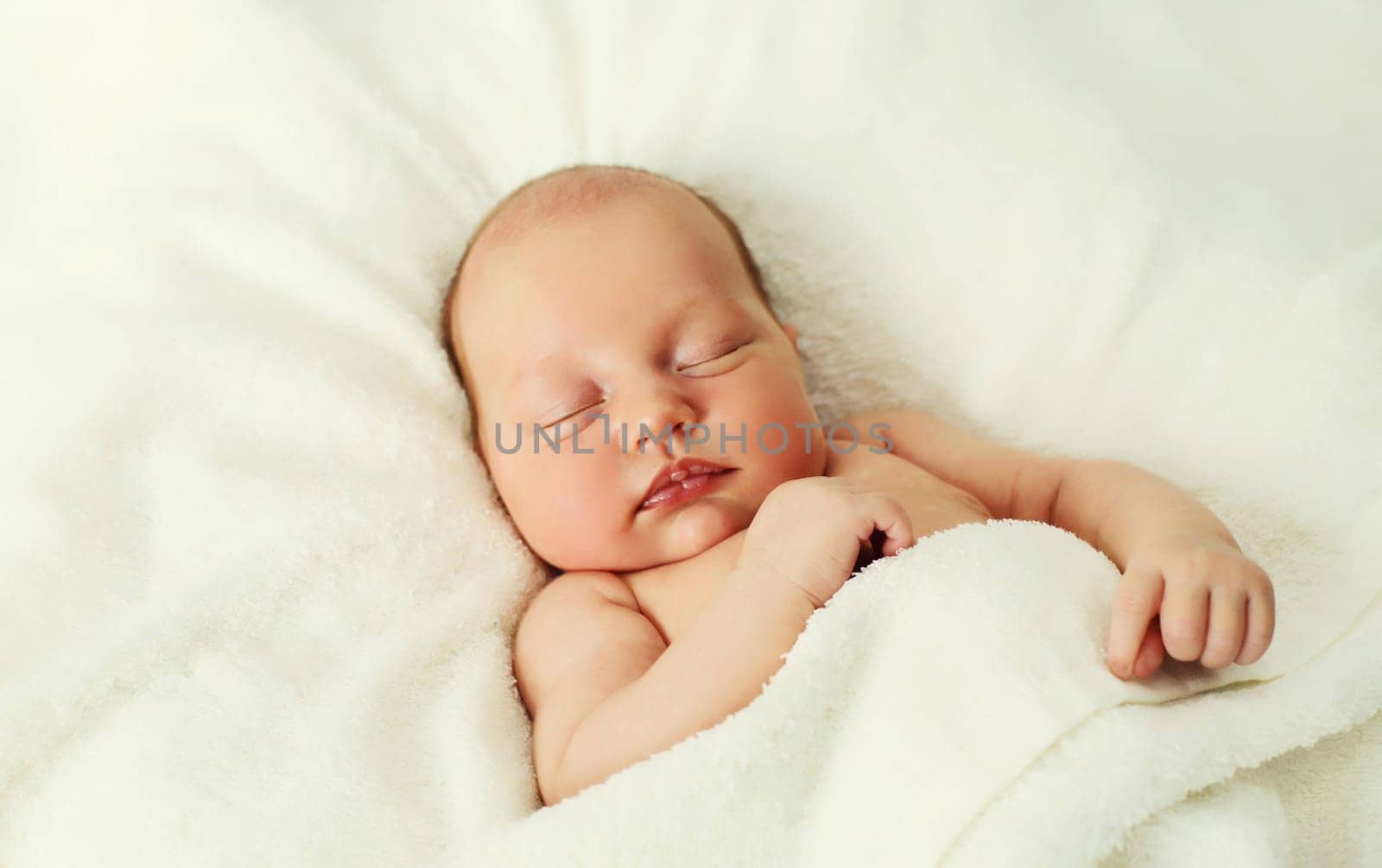 Close up portrait of infant sweet sleeping lying on white bed at home