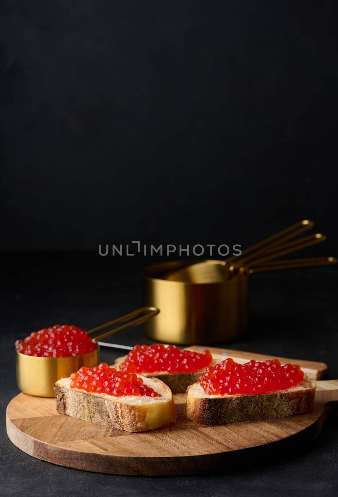 Red caviar on slices of white wheat bread on a black table, concept of luxury and gourmet cuisine