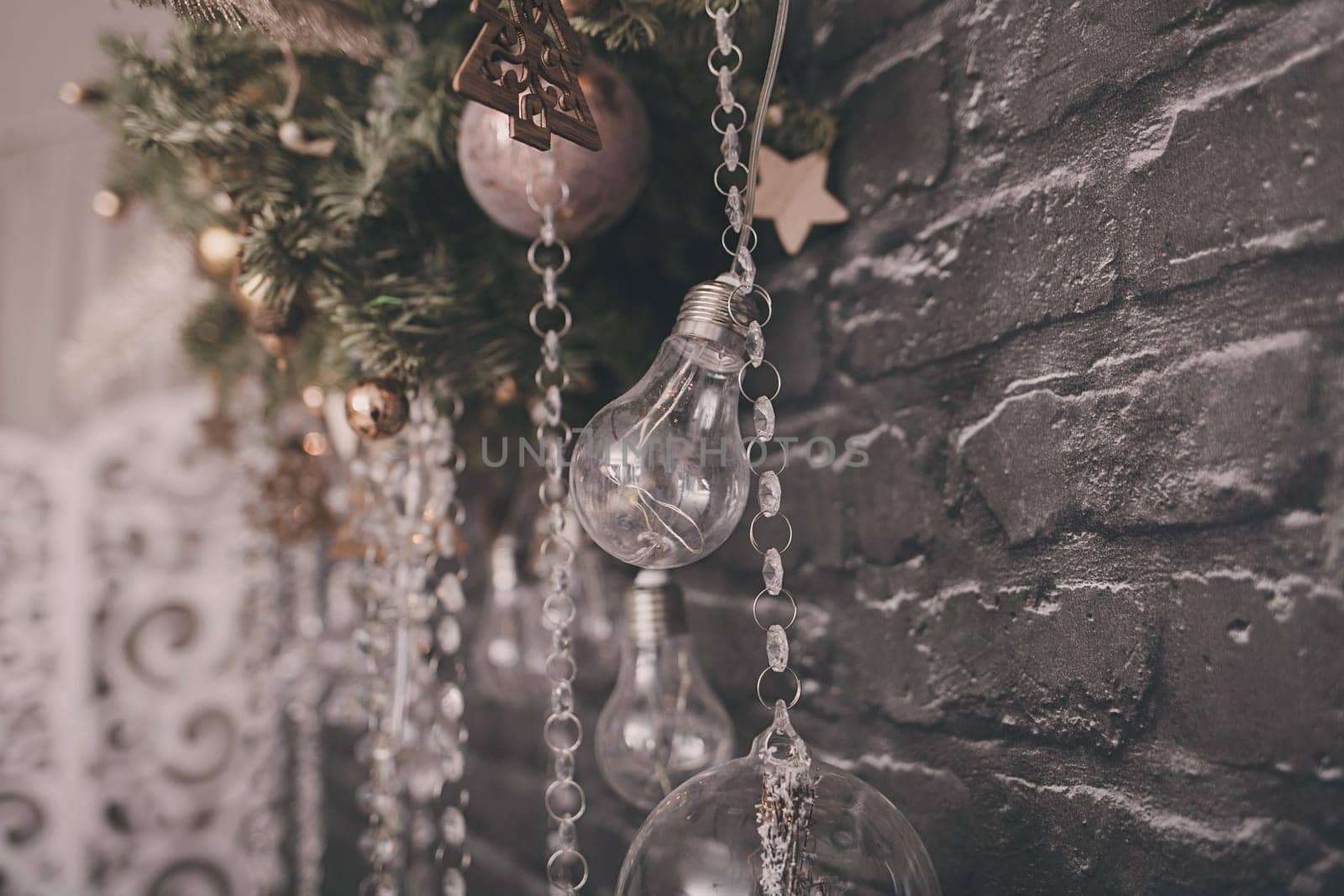 Christmas decor in the room. light bulbs and spruce hanging on a brick wall