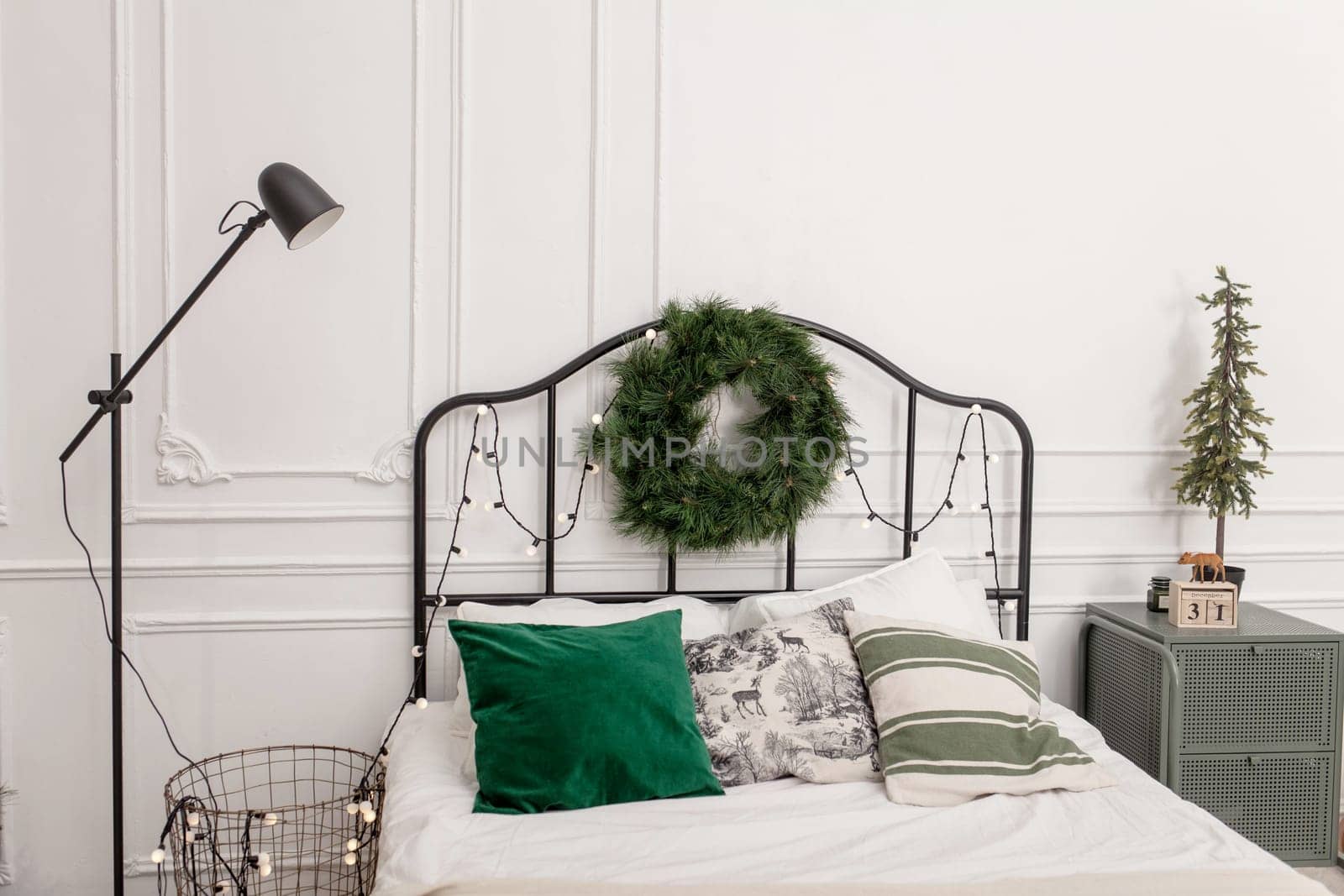 Bedroom interior with bed decorated Christmas tree, gifts, plaid and pillows.