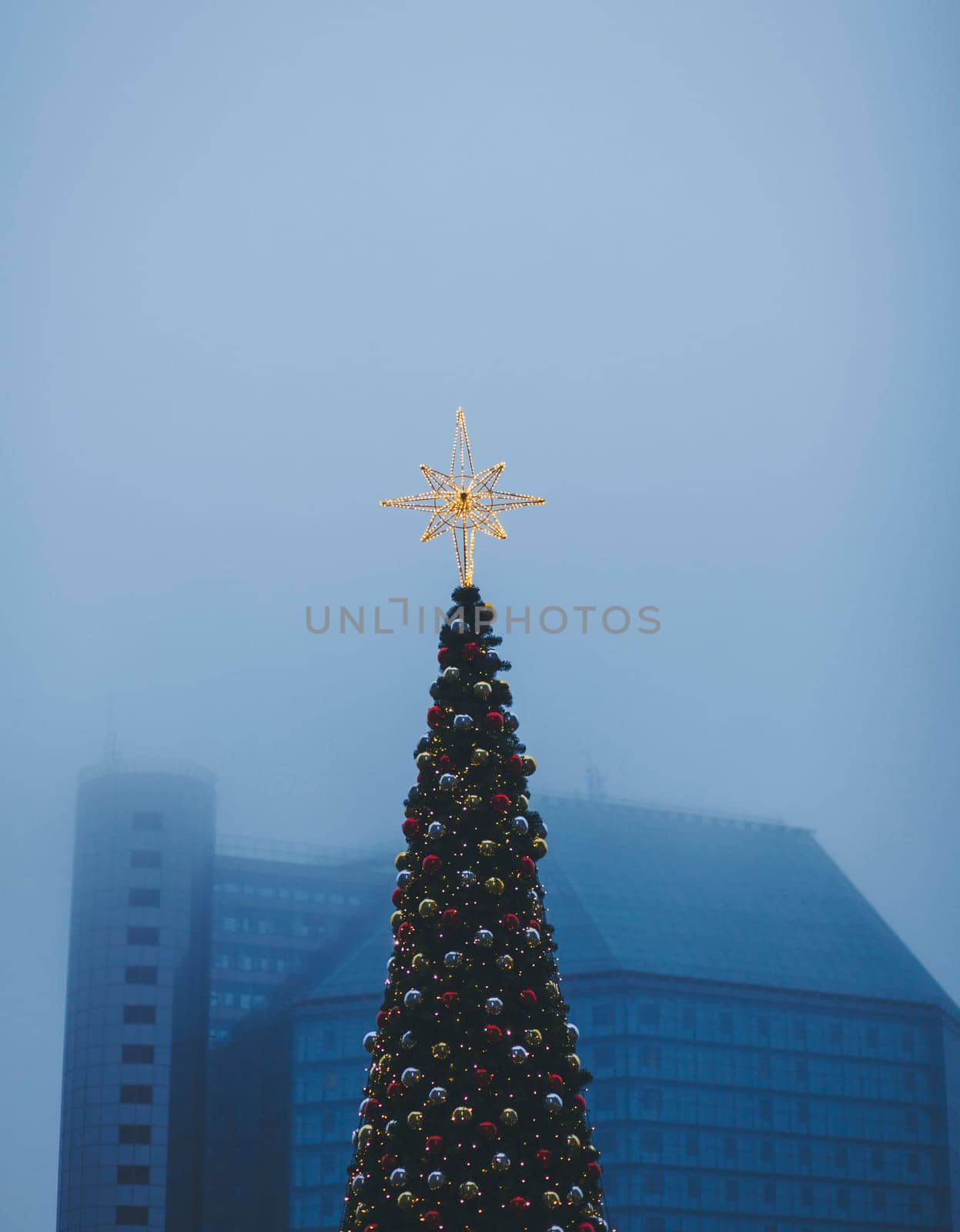 decorated with shining Christmas star and baubles on background of the misty city