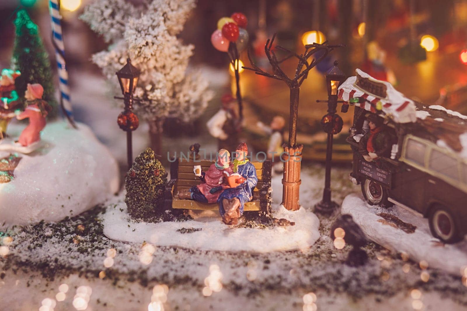 Traditional miniature Christmas village. two people sitting on a bench on new year's eve