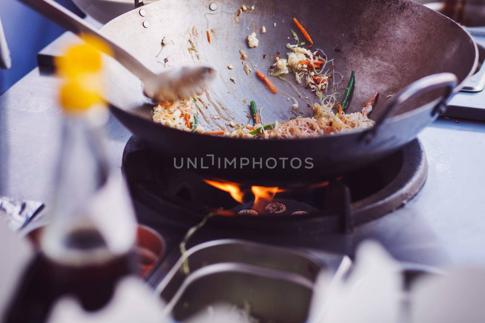 street food. fried noodles in a wok with chicken on the open fire
