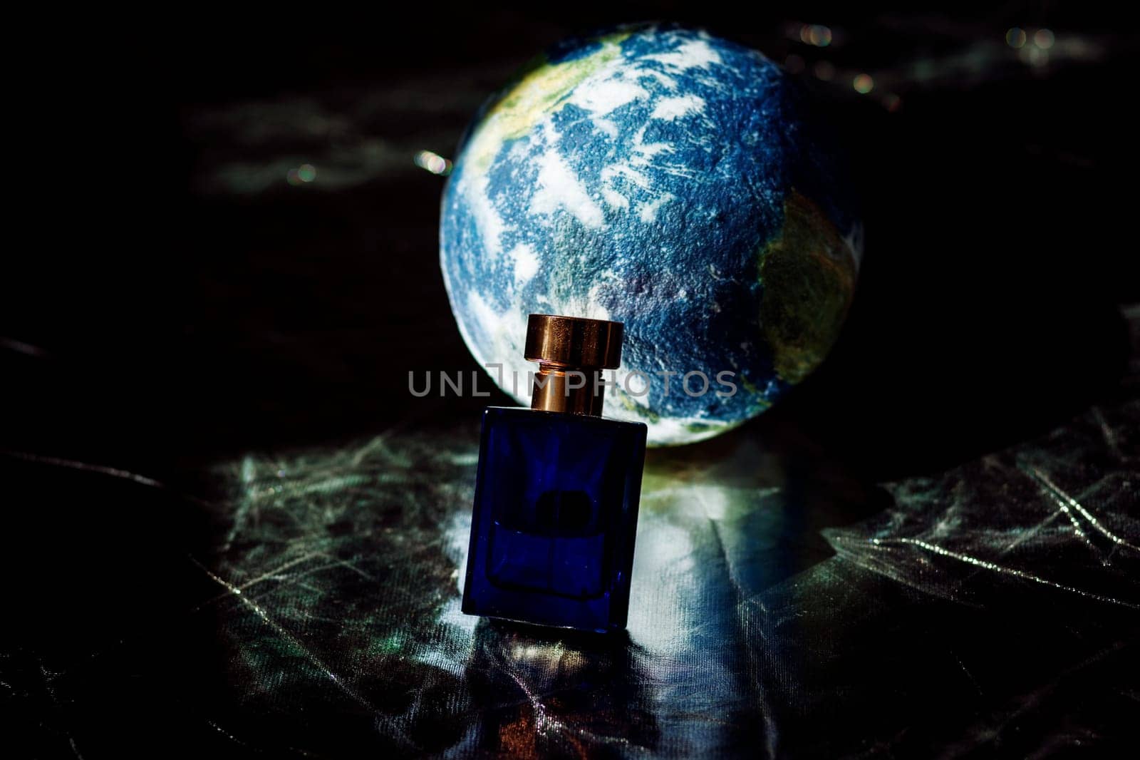 perfume in a blue bottle on the background of a mock-up of the earth. ecological concept. caring for the planet