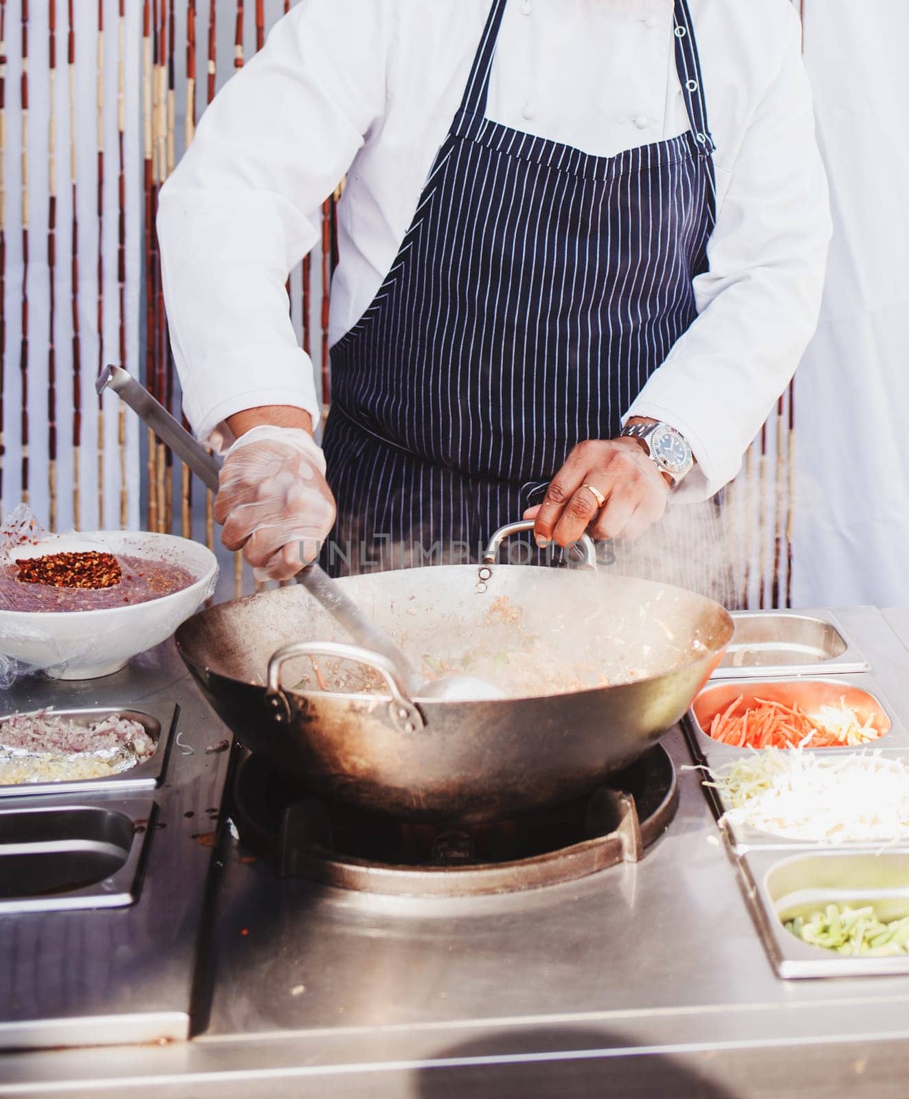 Chef stirs vegetables and noodles in wok