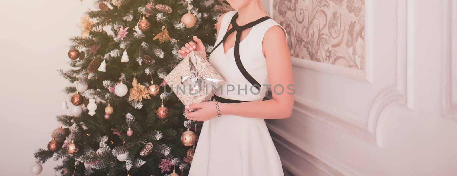 Happy young woman with box near christmas tree 