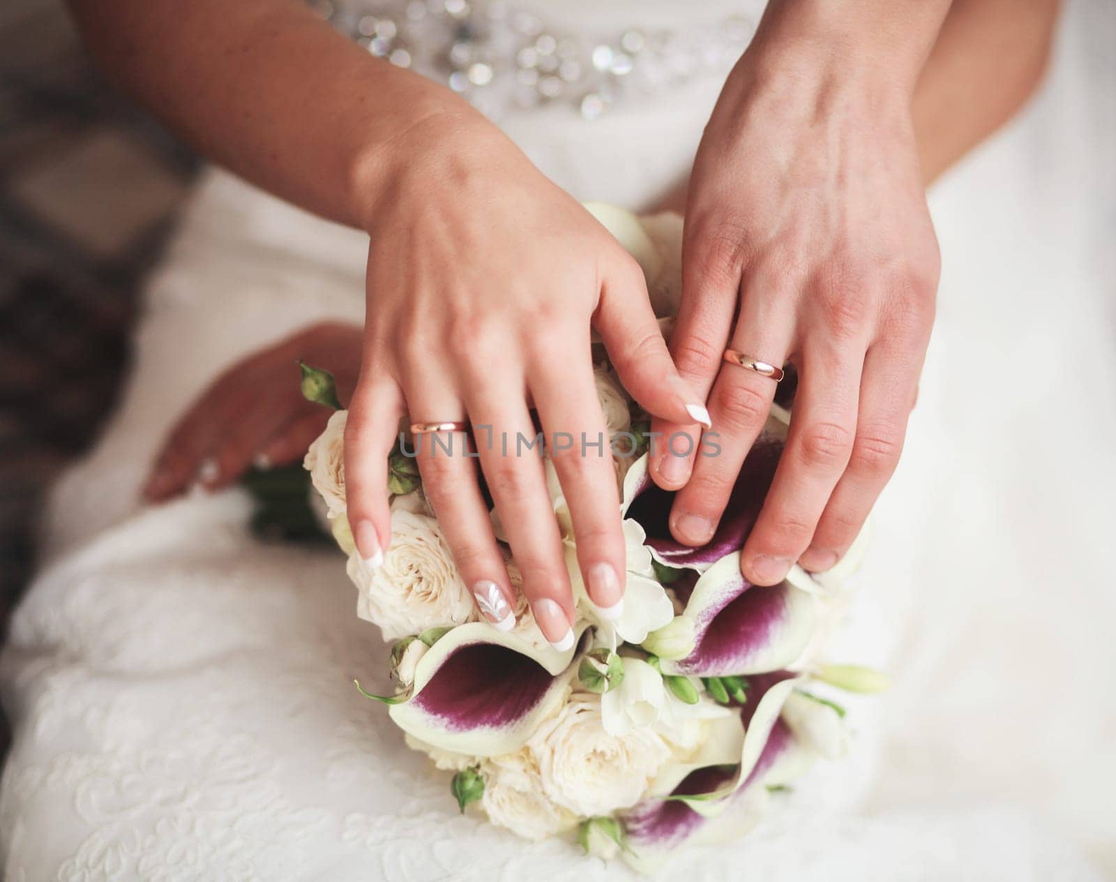hands of the bride and groom with rings on the background of the wedding bouquet