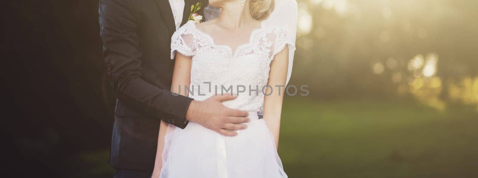 romantic wedding couple embracing at sunset in meadow