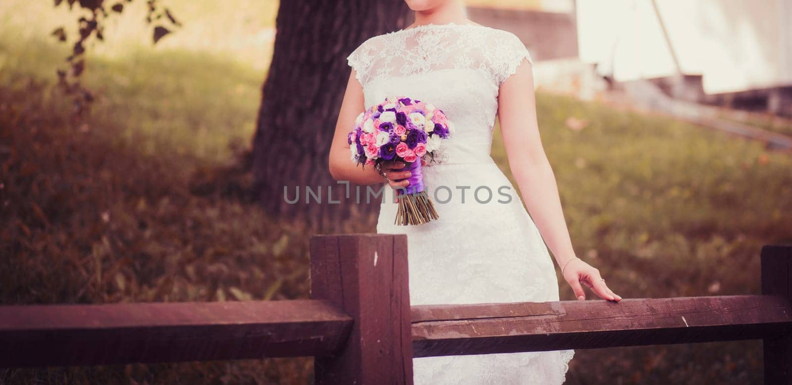 bride in lace wedding dress with bouquet color outdoors