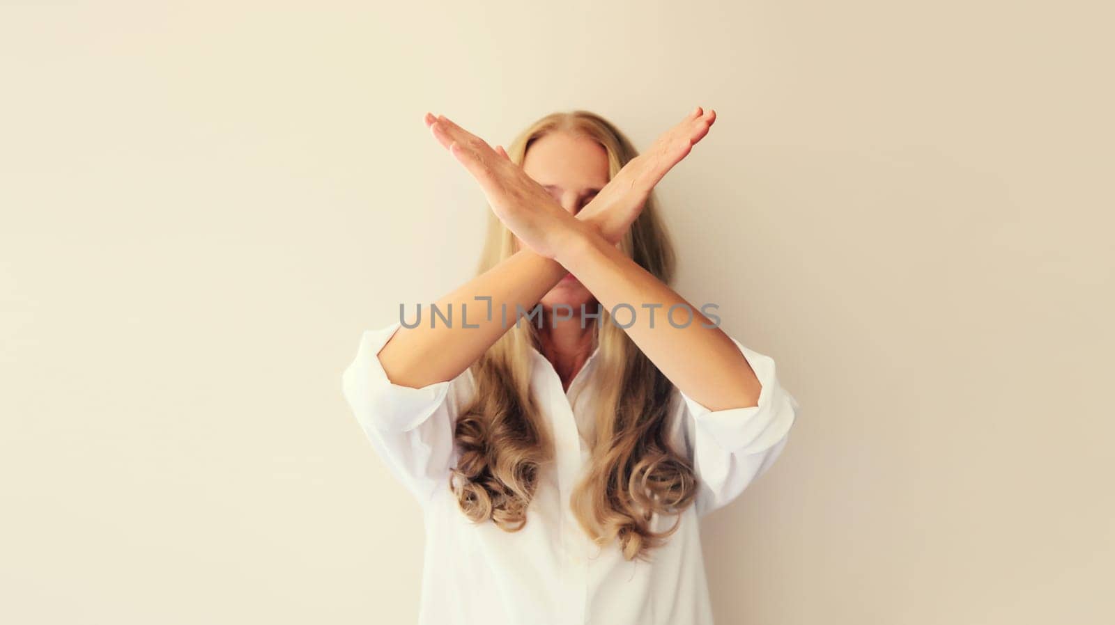Upset young woman shows stop, no or enough sign with palm of hand, refusal gesture, domestic violence